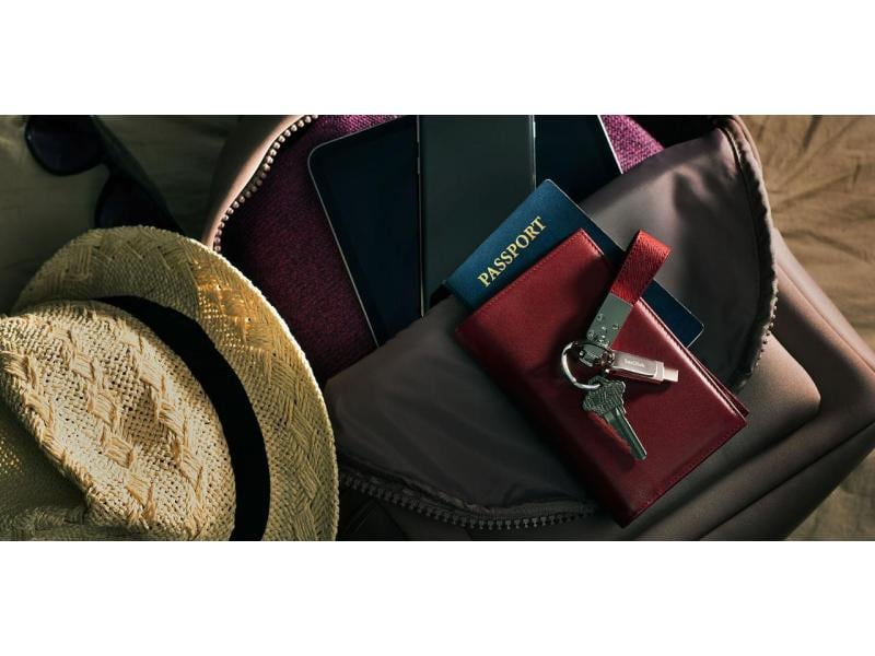Offene Tasche mit Hut, Reisepass, Geldbörse, Schlüsseln und Telefon. Gegenstände sind teilweise sichtbar.