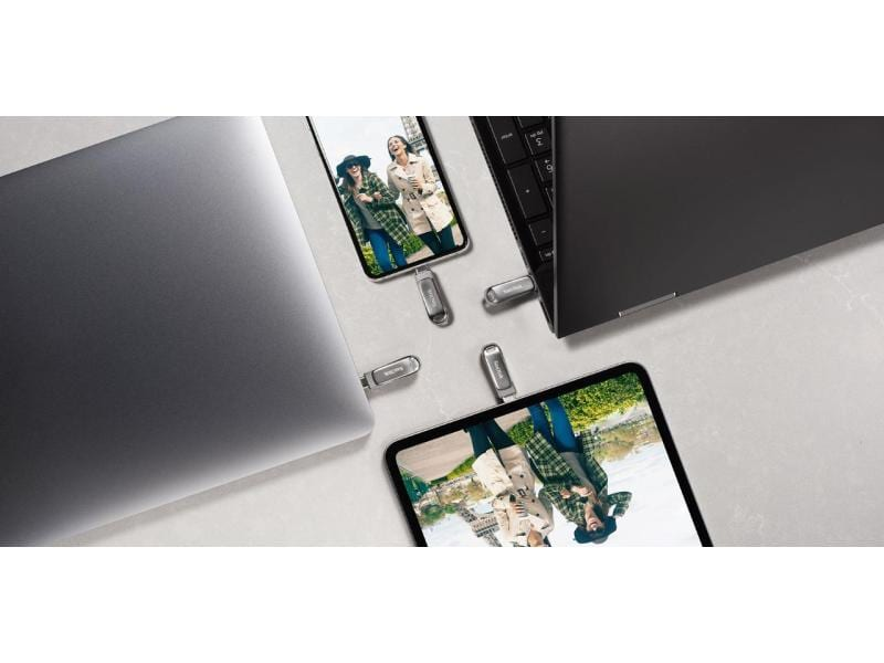 Unità flash USB, vicino a laptop e tablet, che mostrano un'immagine di due donne con un cappotto.