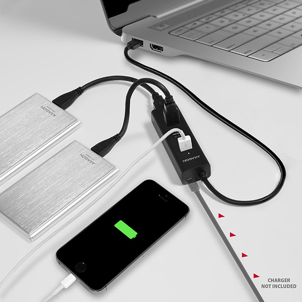 Laptop USB-hubhoz, két merevlemezhez és egy fekete telefonhoz csatlakoztatva töltődik.