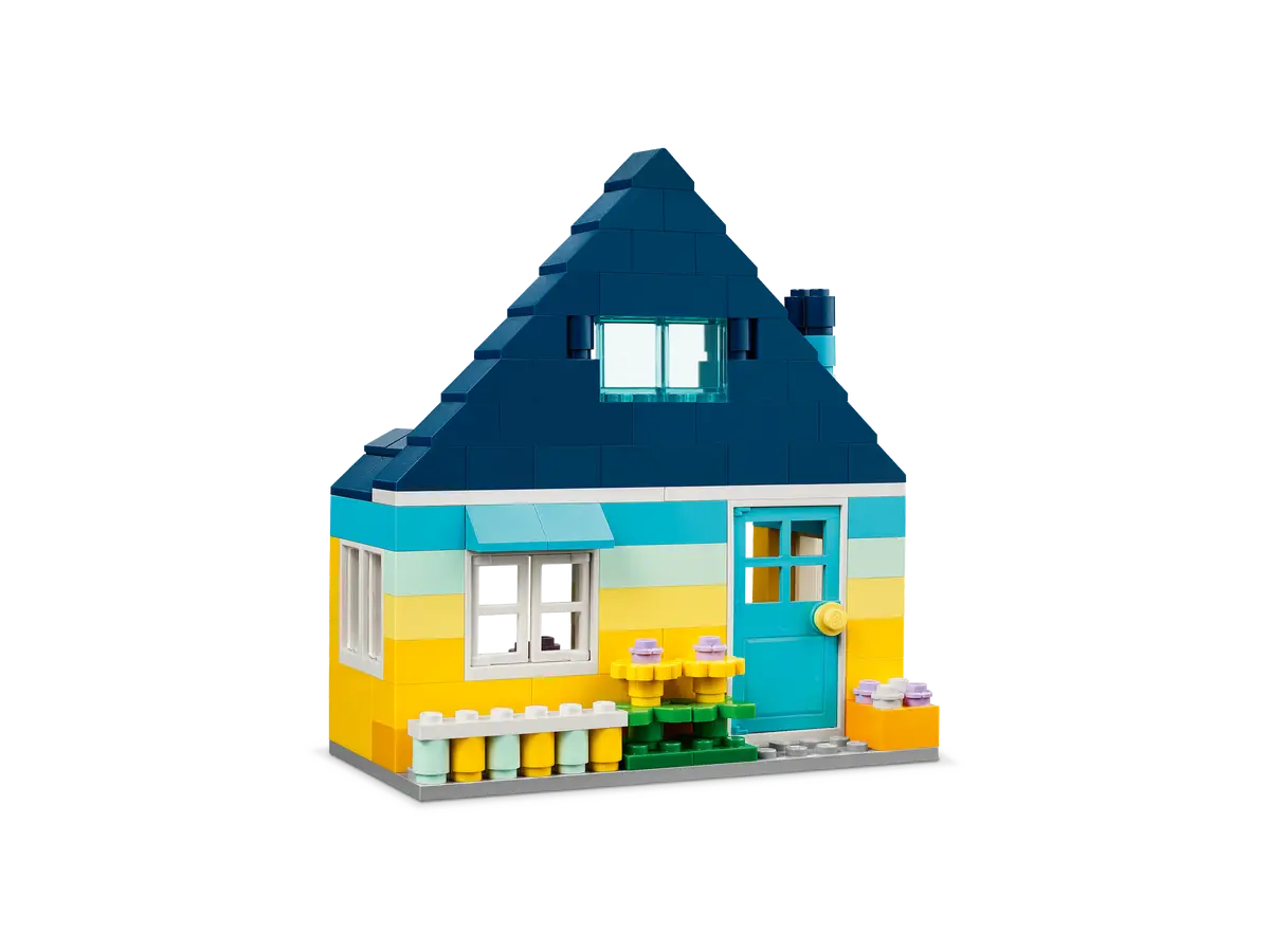 Kolorowy model domu Lego z niebieskim dachem, żółtymi ścianami i zieloną trawą.
