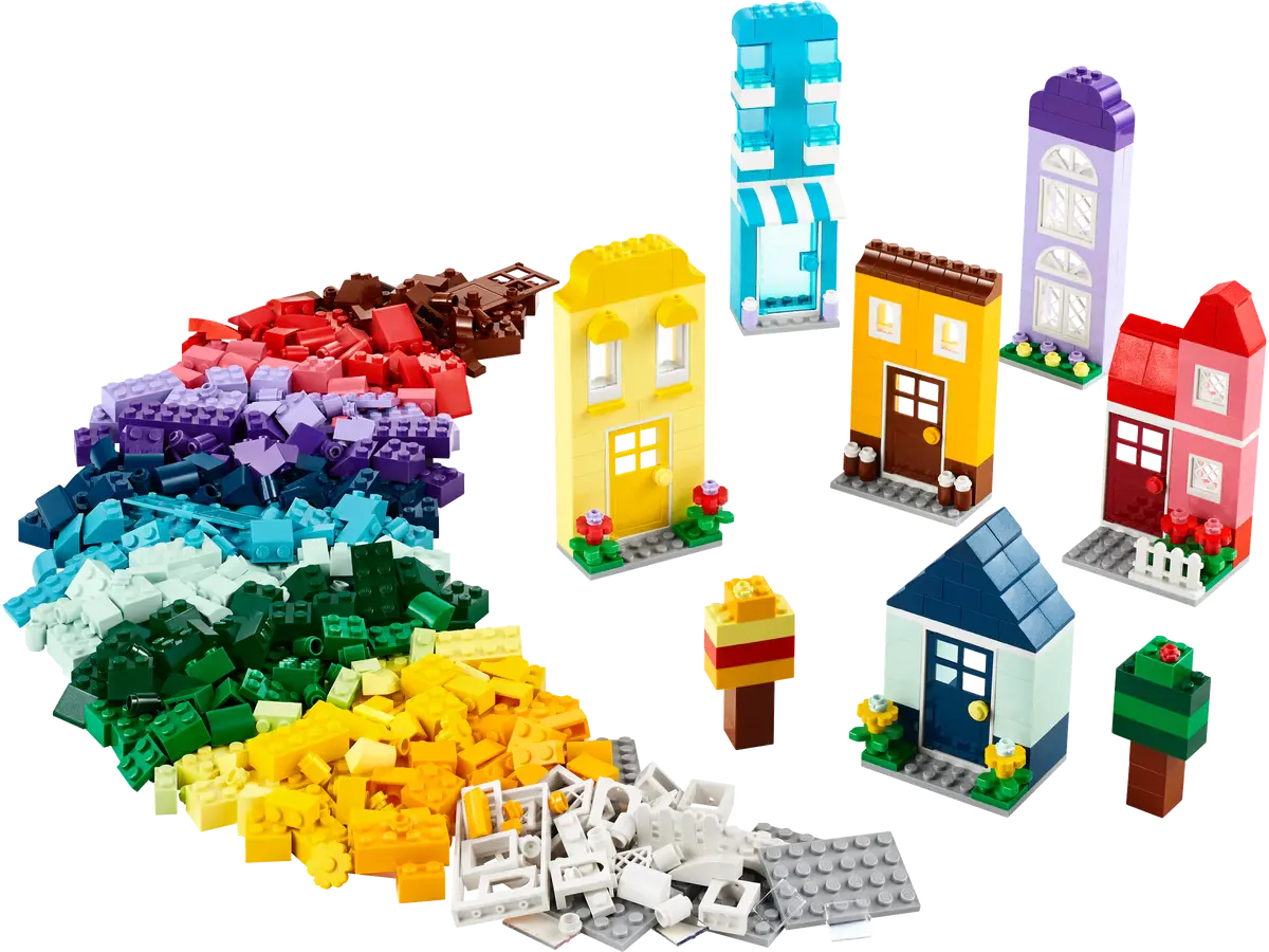 Zestaw Lego z kolorowymi klockami i małymi domkami na białym tle.