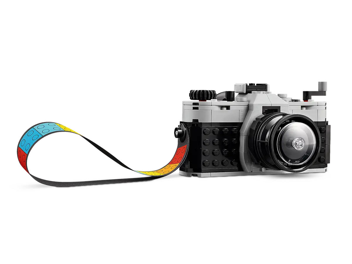 Model aparatu LEGO z kolorowym paskiem. Jest szary, czarny i biały. Czarne tło.
