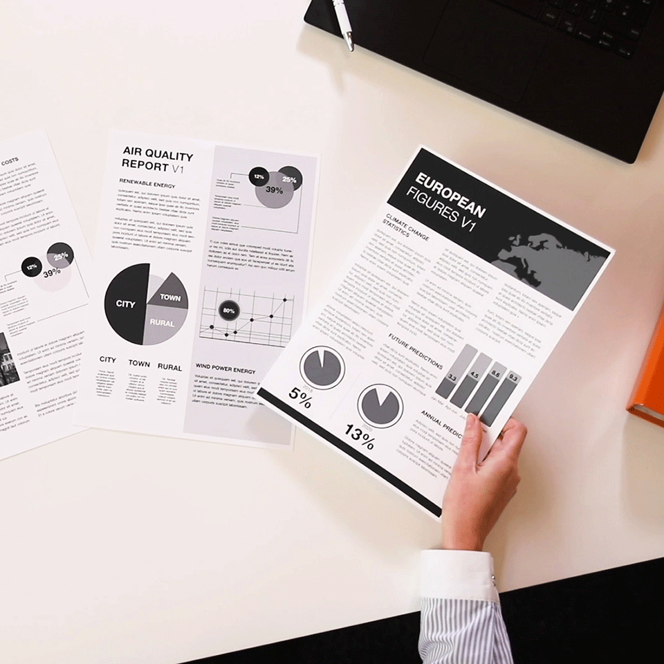 Documenti con grafici e diagrammi su una superficie bianca. Mano che tiene un documento.