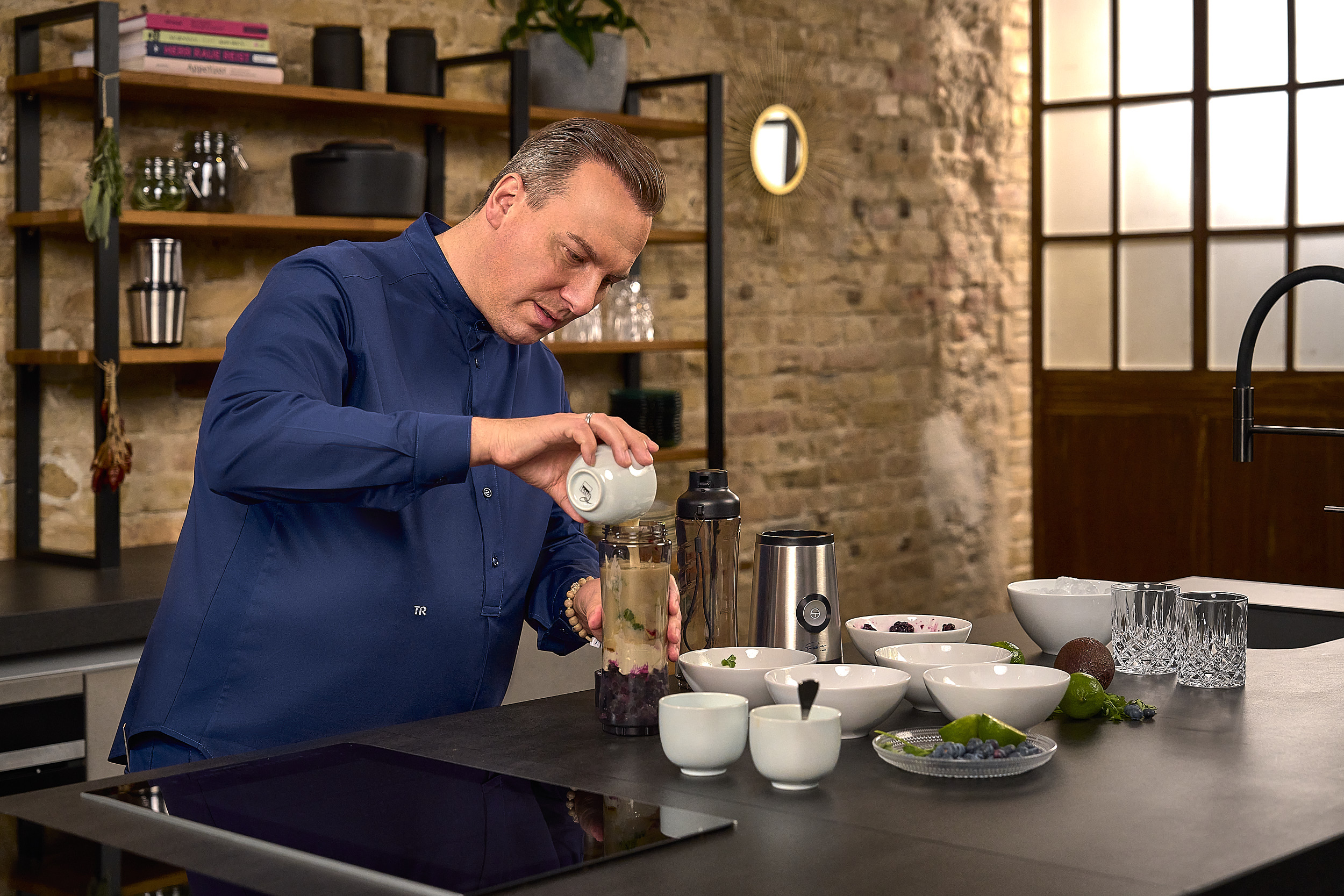 Mann in der Küche, der einen Smoothie zubereitet.