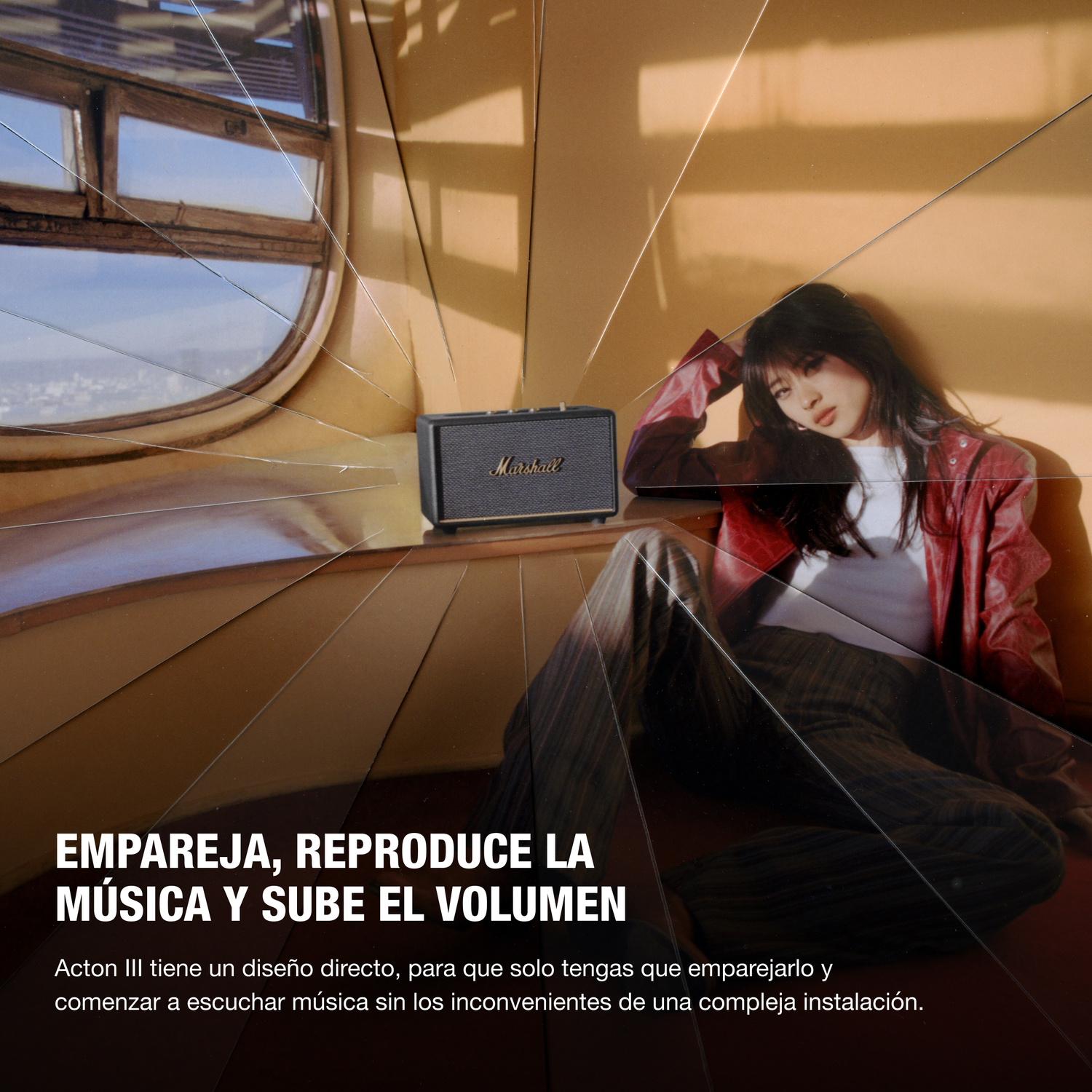 Altavoz Marshall negro sobre una mesa. Mujer en chaqueta roja y pantalones cerca.