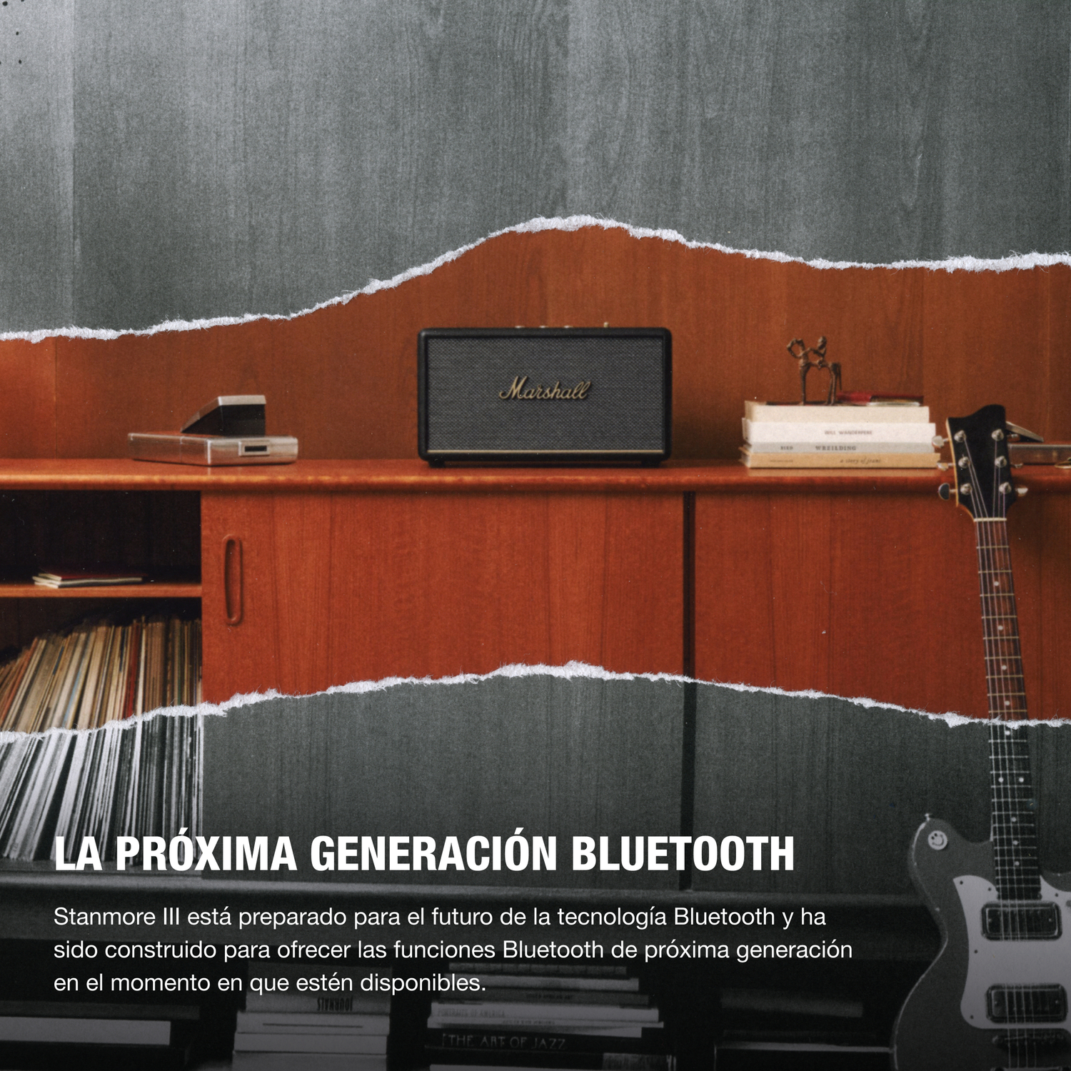 Un altavoz Marshall sobre un mueble de madera. Se ven una guitarra y libros.