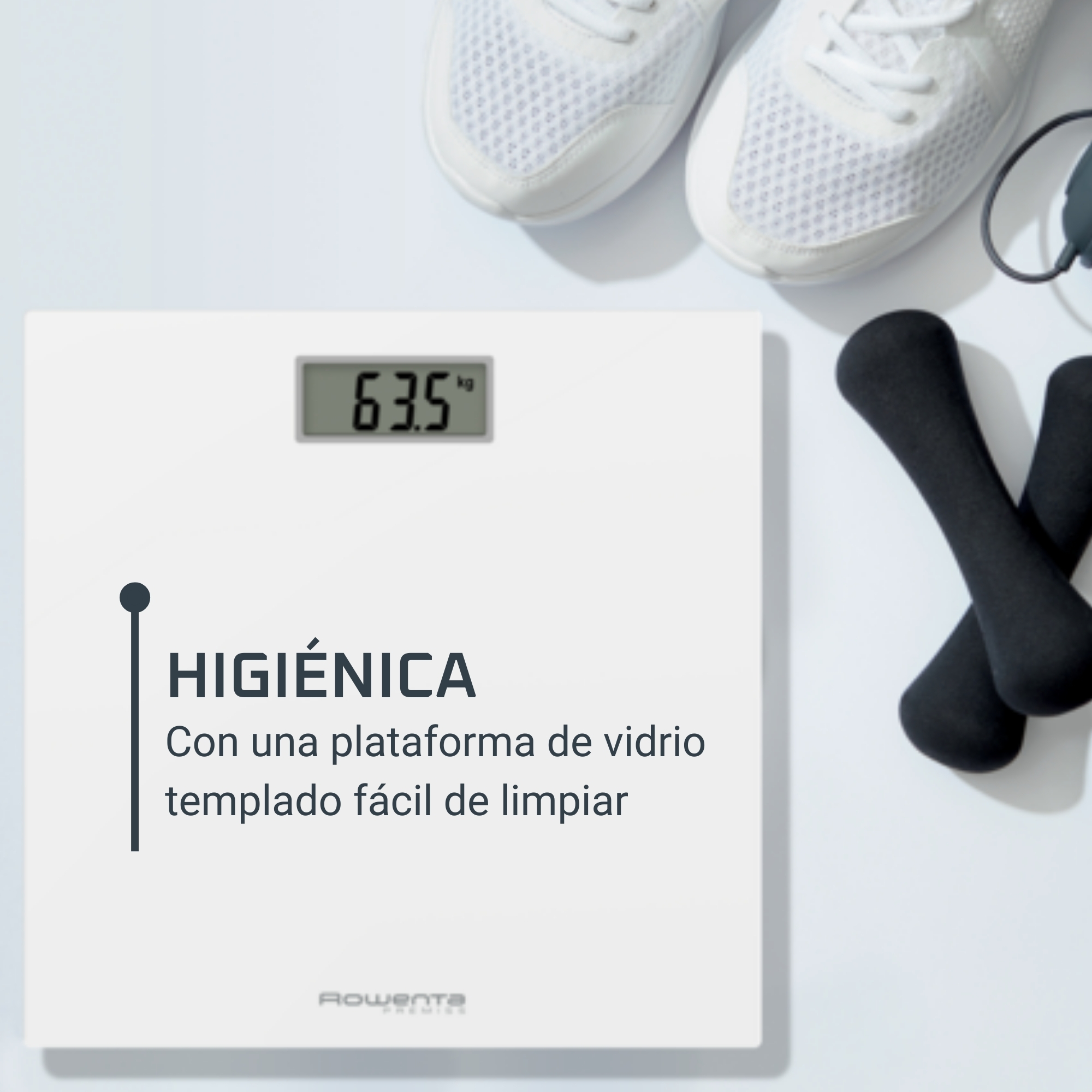 Una báscula blanca con pantalla digital que muestra 63,5 kg. Mancuernas y zapatos en el fondo.