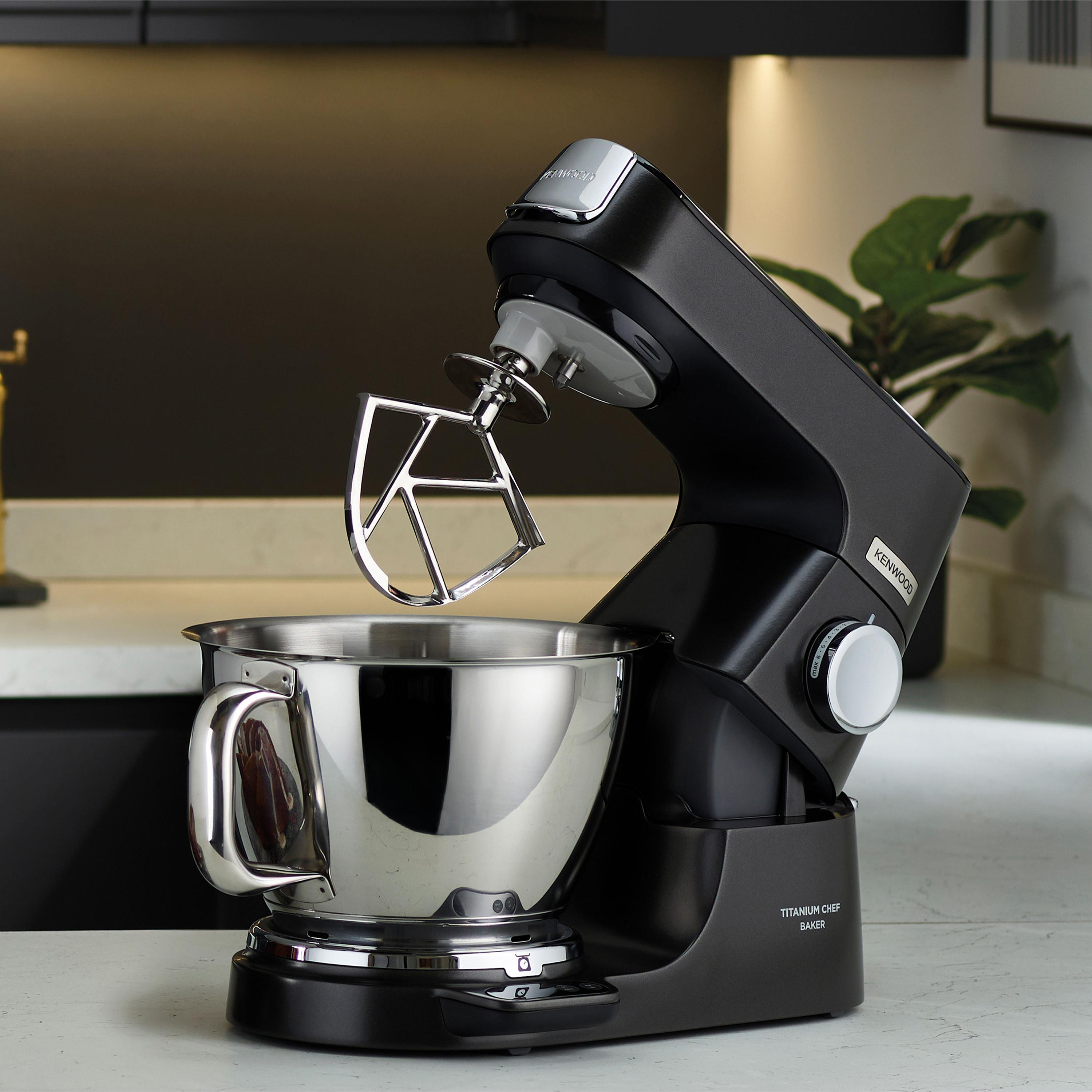Schwarzer Kenwood Küchenmixer mit einer silbernen Schüssel auf einer weißen Arbeitsplatte.