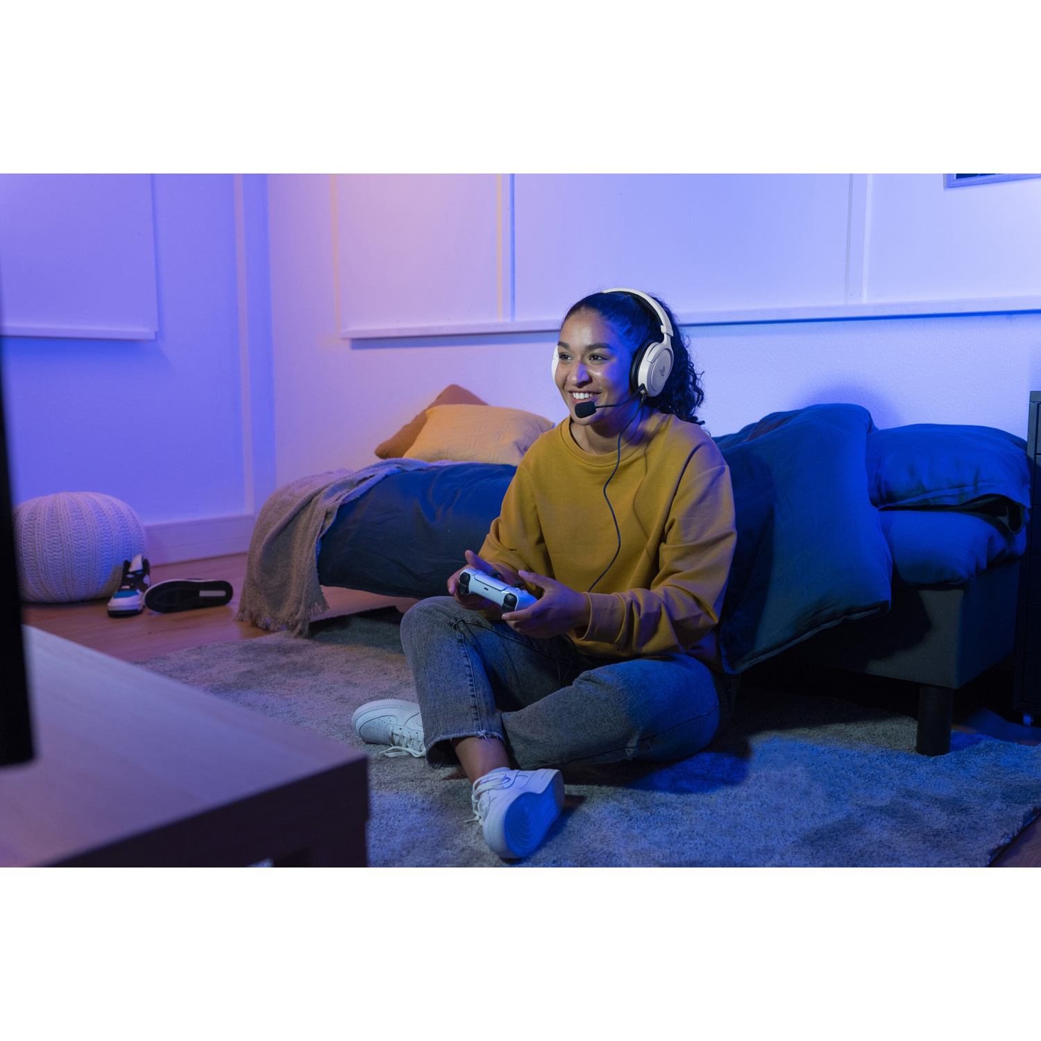 Una donna che gioca a un videogioco con un auricolare. La stanza ha un'illuminazione blu e viola.