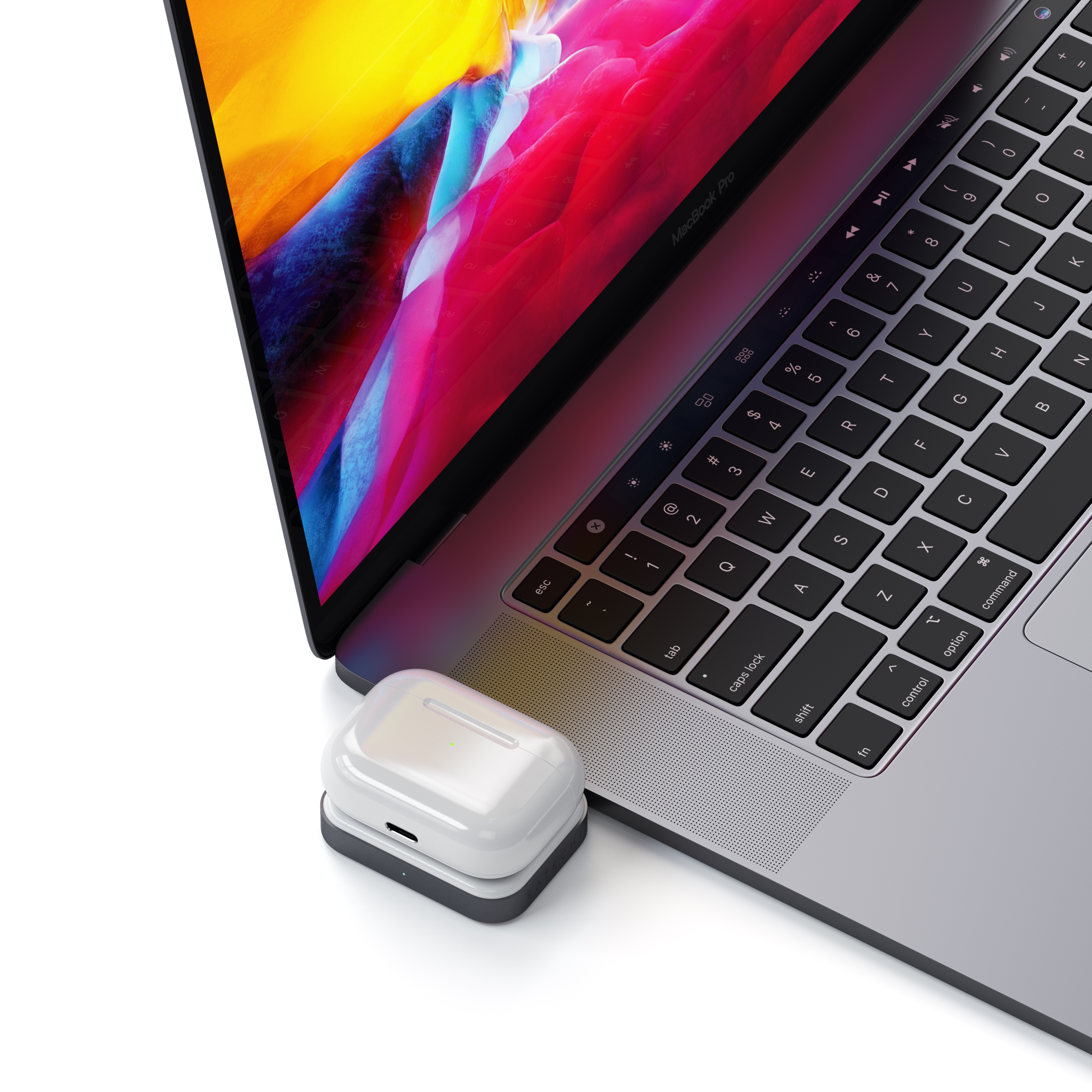 Egy laptop színes képernyővel és egy fehér töltőtok fekete alappal mellette.