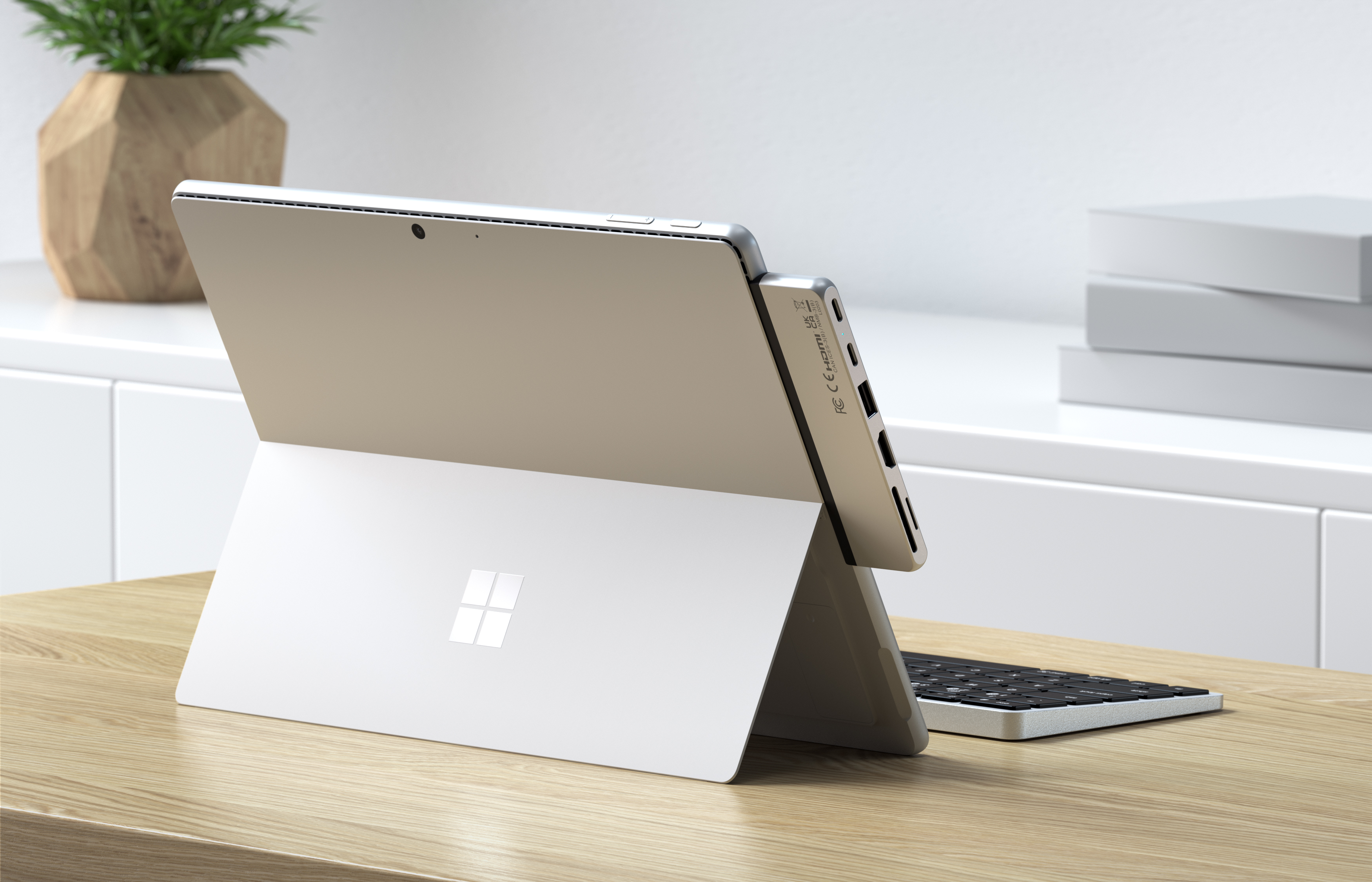 Ezüst tablet stílusú laptop fehér billentyűzettel az asztalon.