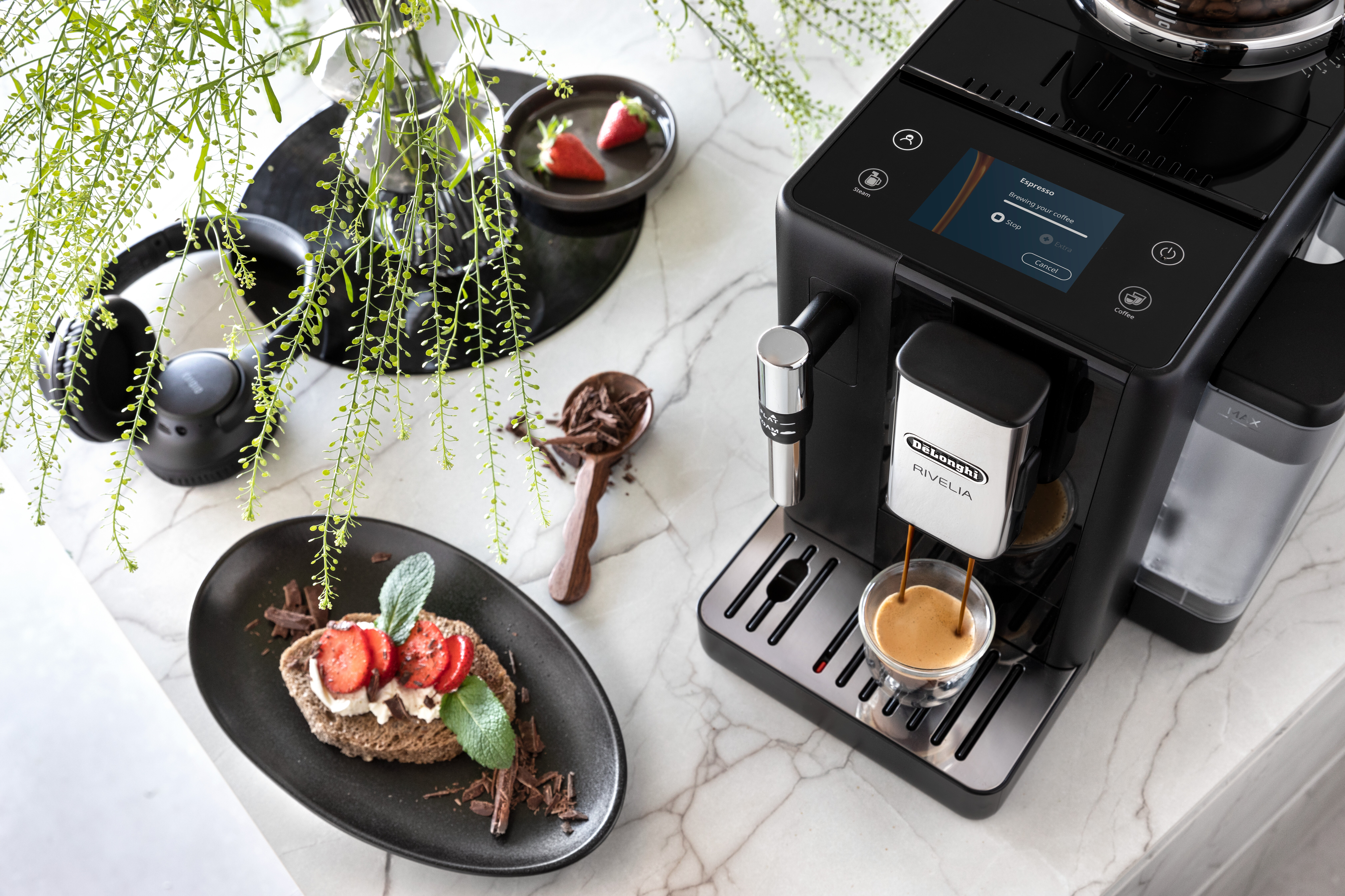 Espressomaschine, die Kaffee brüht, mit einem Teller Kuchen und einer Schüssel Erdbeeren in der Nähe.