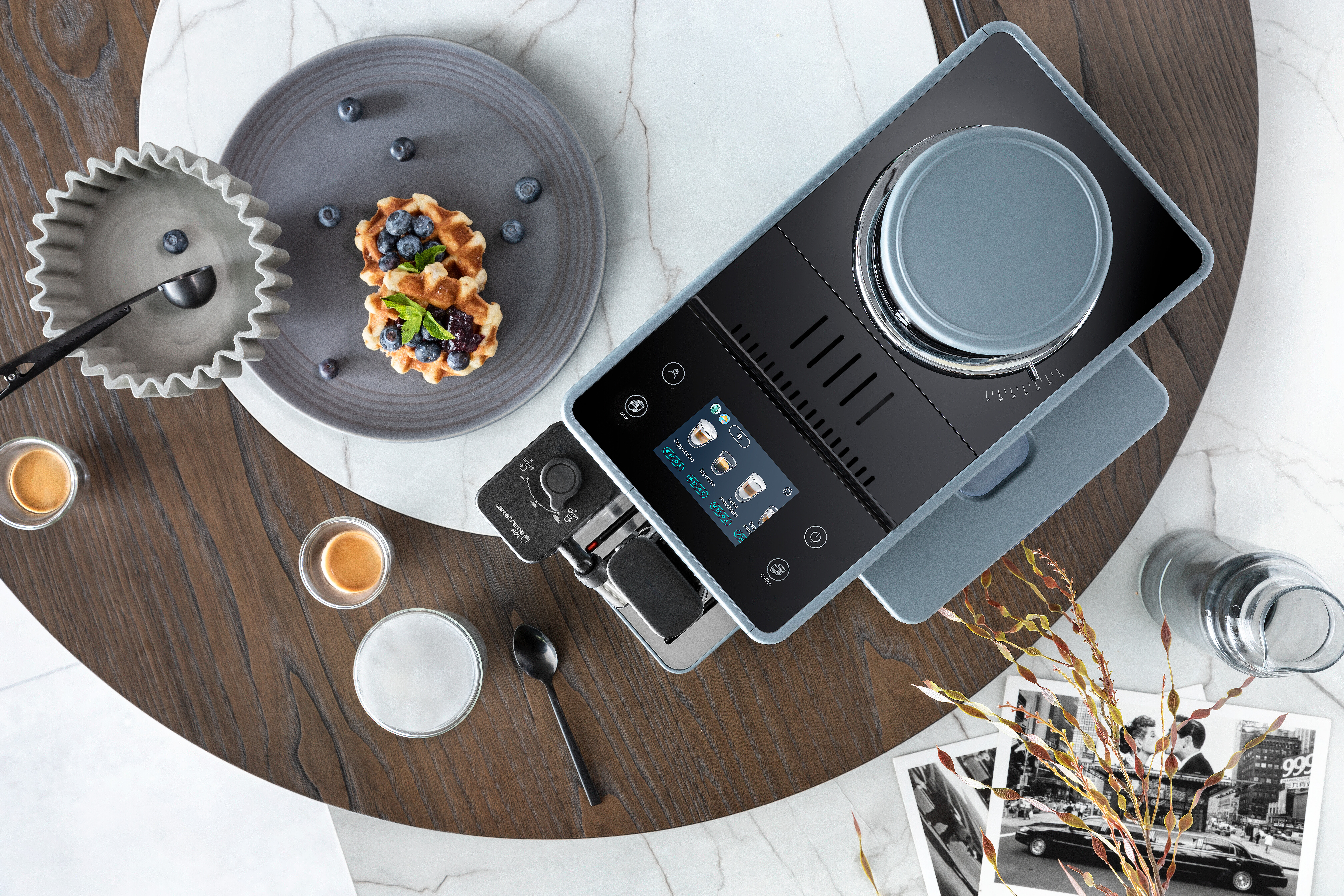 Eine moderne Kaffeemaschine mit Waffeln und Blaubeeren. Die Szene ist auf einem Holztisch aufgebaut.