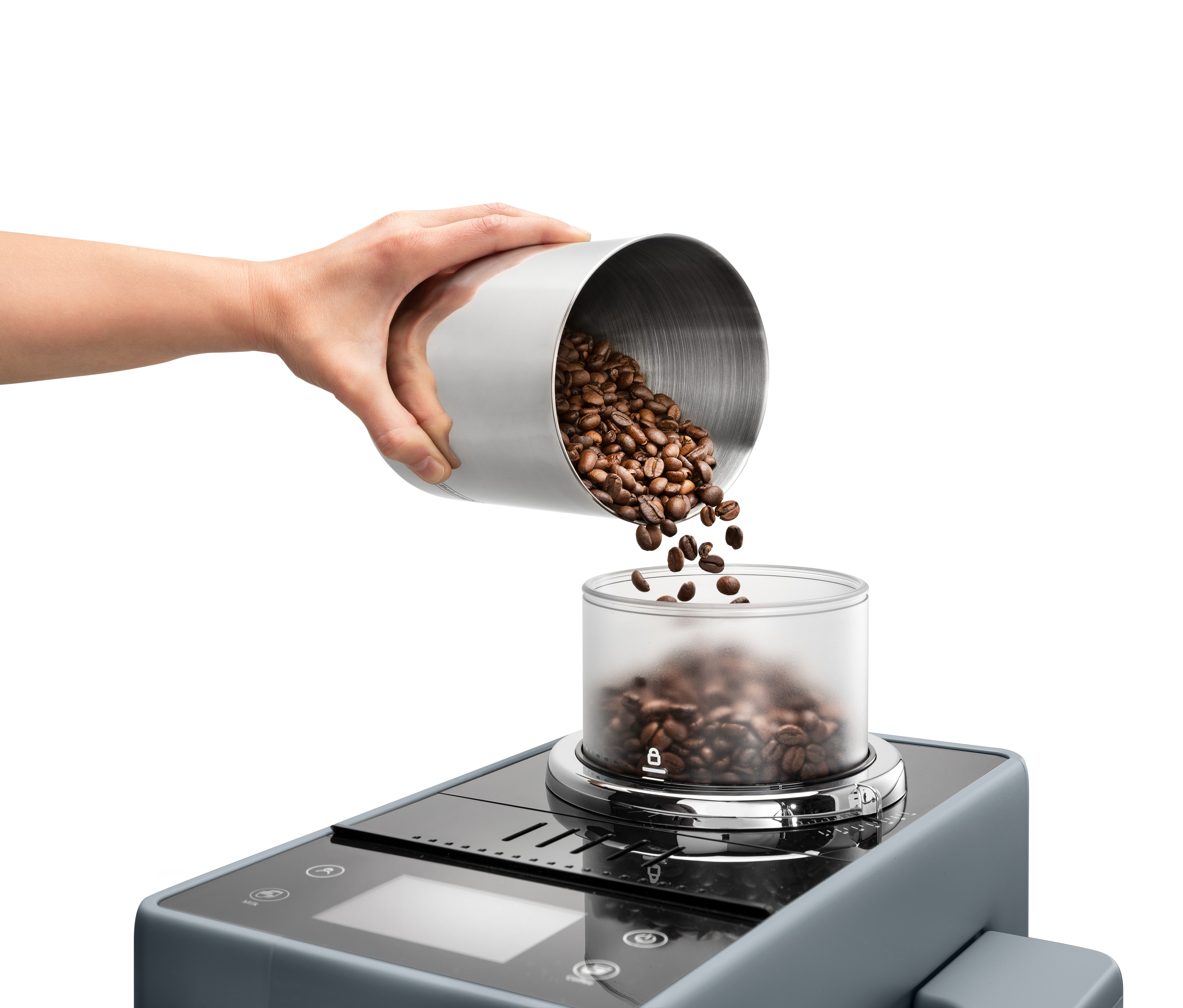 Eine Hand gießt Kaffeebohnen aus einem Metallbehälter in einen transparenten Behälter auf einer Maschine.
