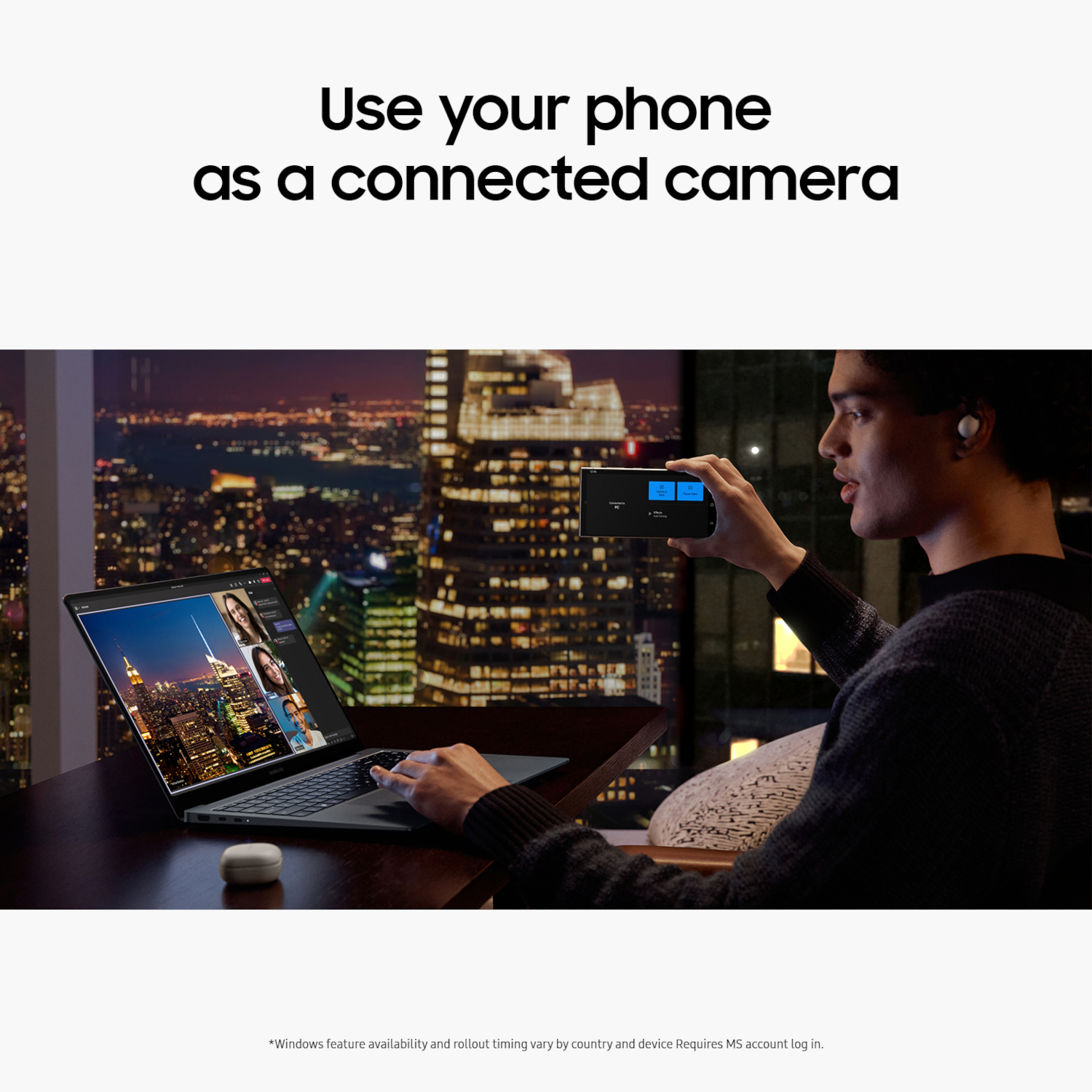 Homme utilisant son téléphone comme caméra connectée. Ordinateur portable ouvert, fond de paysage urbain, pièce sombre.
