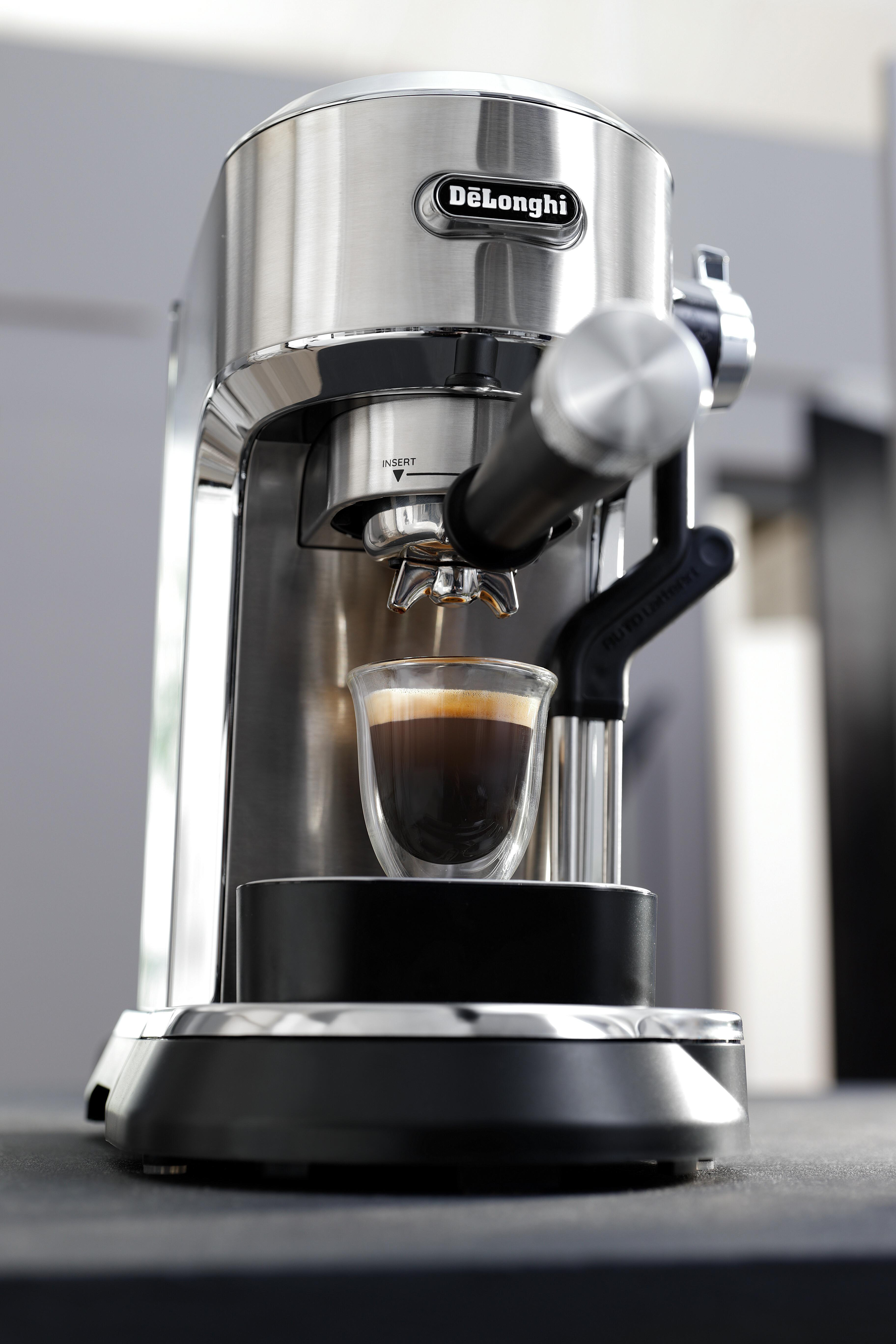 Eine DeLonghi Espressomaschine mit einem Glas, gefüllt mit Kaffee, auf schwarzem Untergrund.