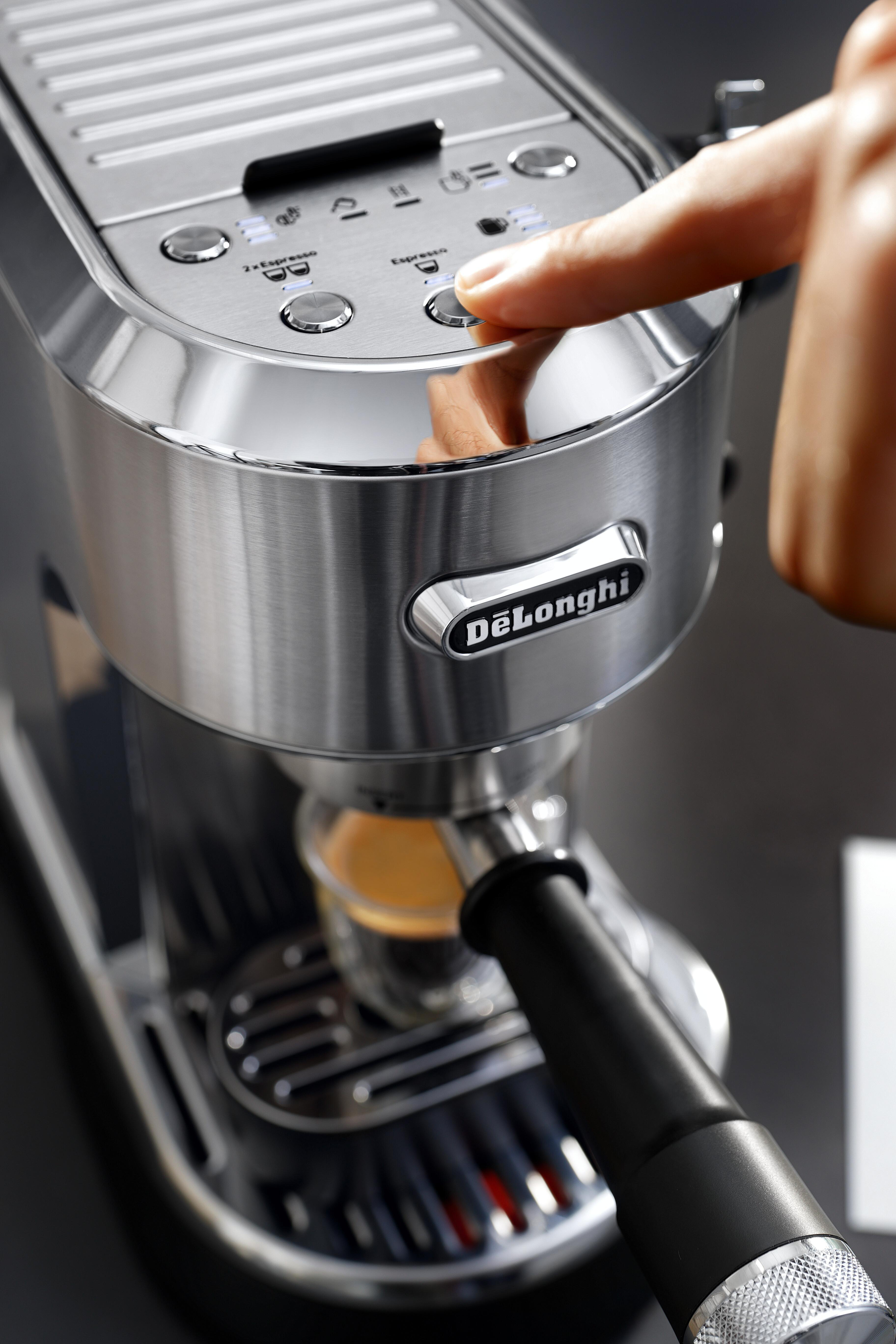 Der Finger einer Person drückt die Espresso-Taste auf einer silbernen Espressomaschine.