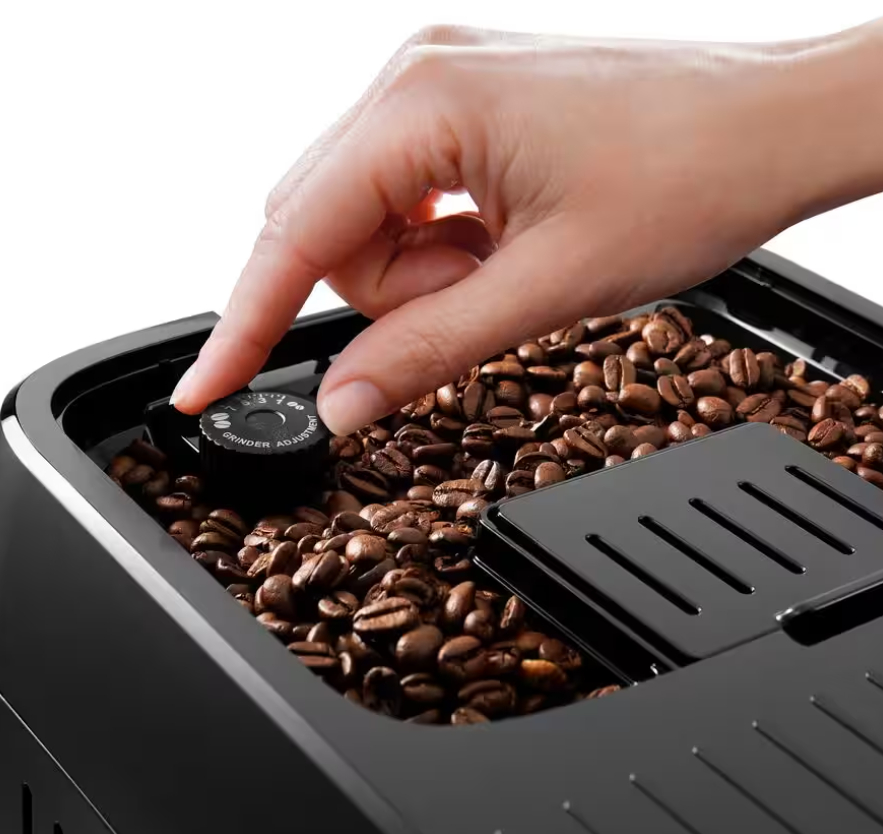 Eine Hand stellt die Mahleinstellung an einer Kaffeemaschine ein. Der Bohnenbehälter ist voll mit Kaffeebohnen.