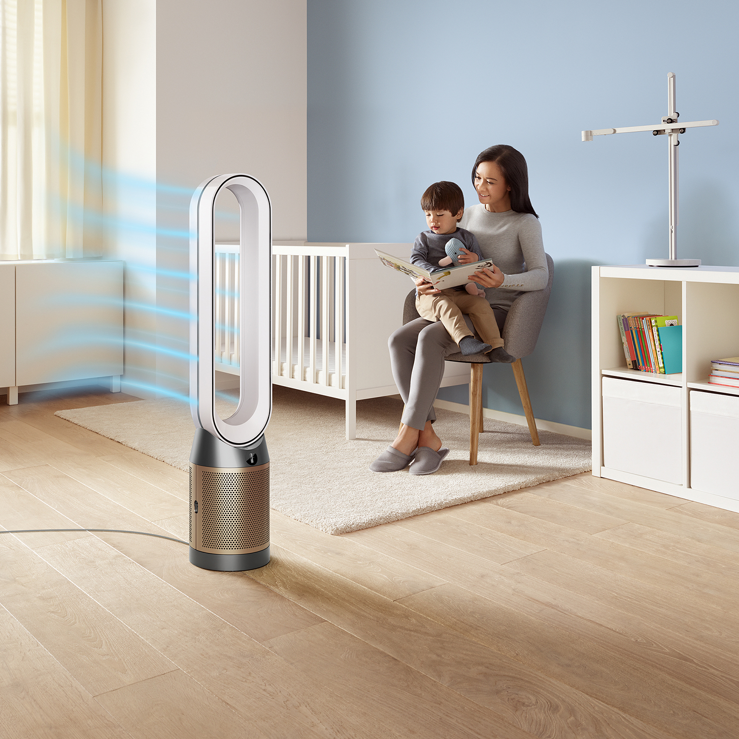 Una donna e un bambino siedono vicino a un purificatore d'aria. Una culla e delle librerie sullo sfondo.