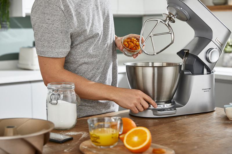 Osoba w kuchni: mieszanie składników mikserem Kenwood, plasterki pomarańczy.