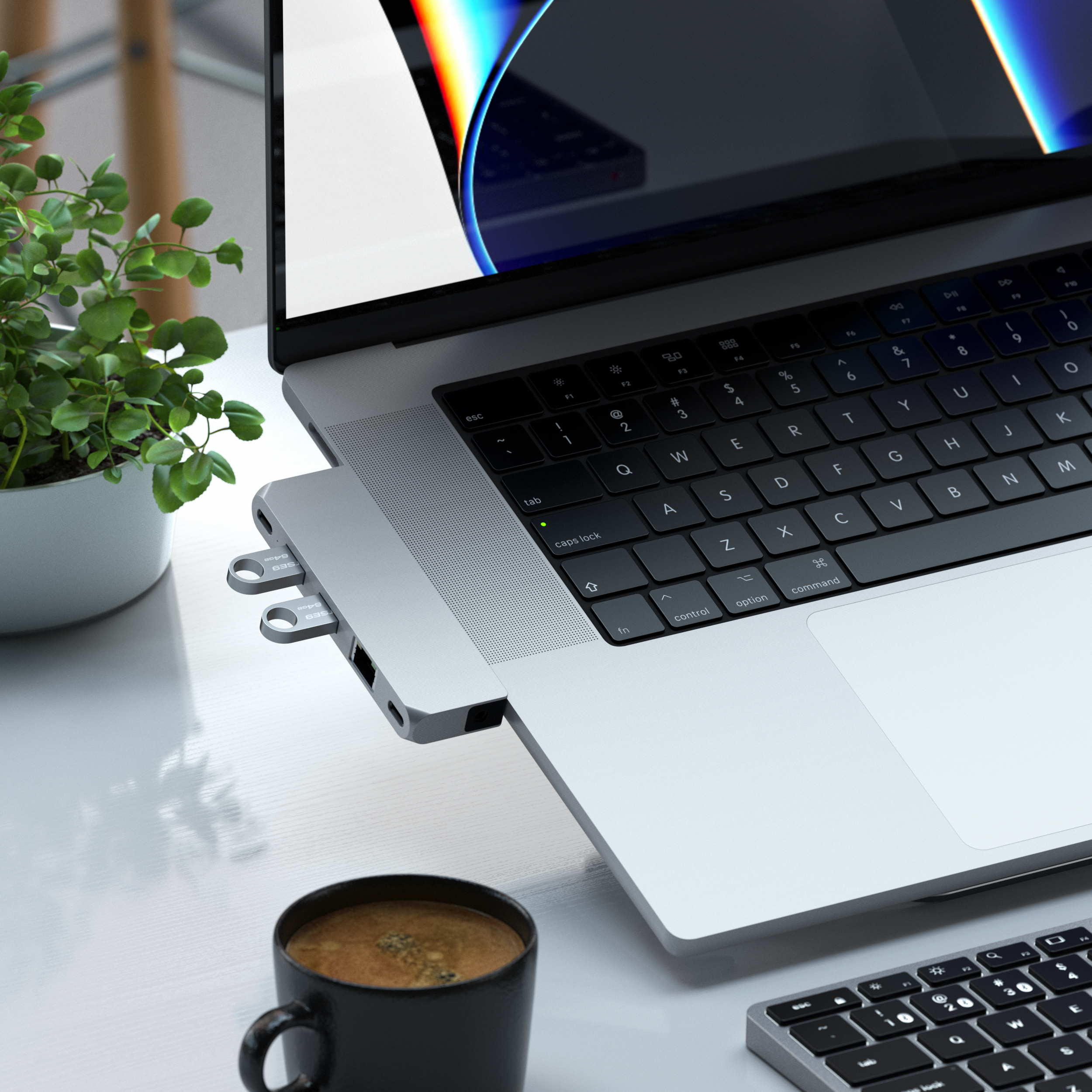 Laptop USB hub-hoz csatlakoztatva, pendrive-okkal, kávéscsészével, billentyűzettel az asztalon.