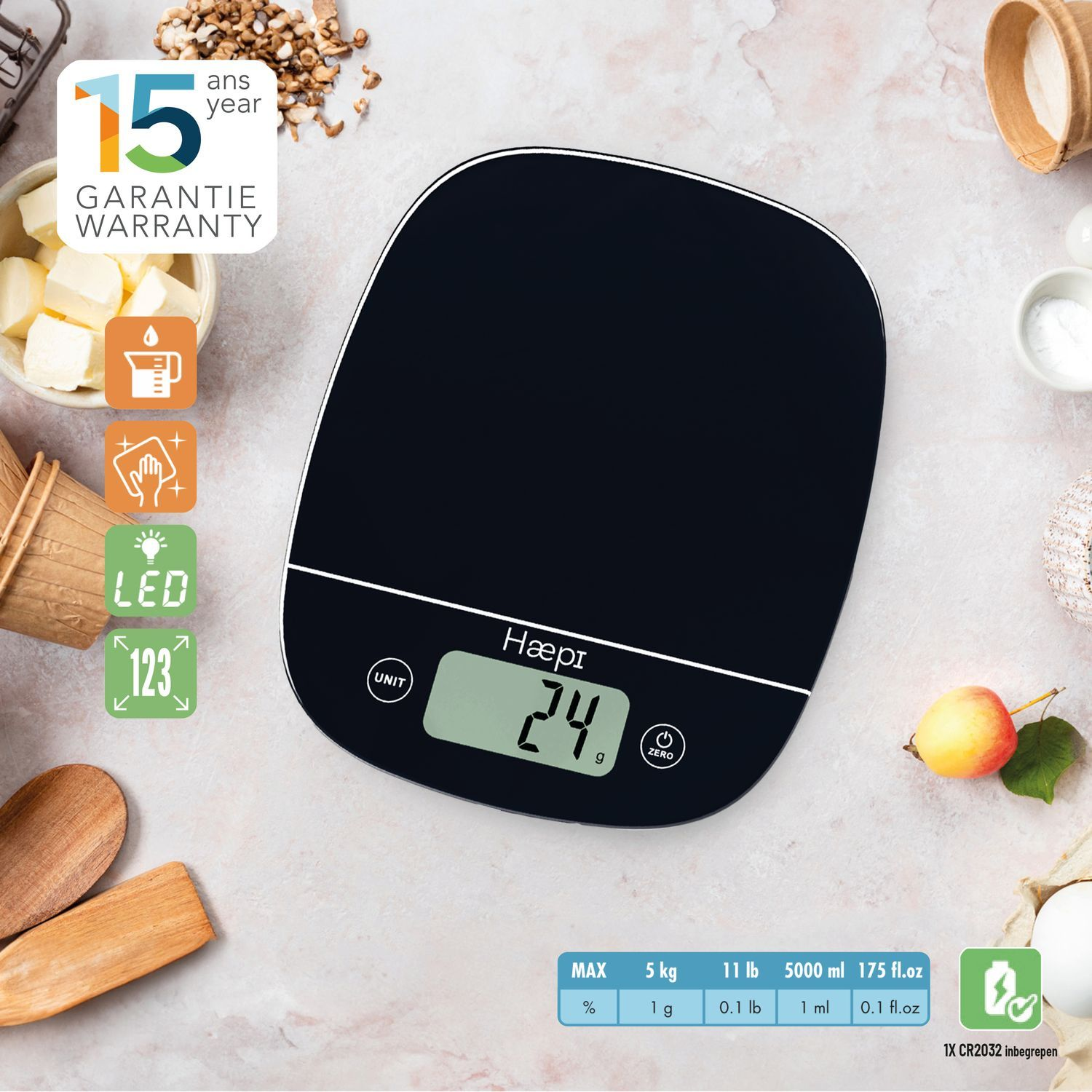 Black digital kitchen scale with food items in the background. White background.