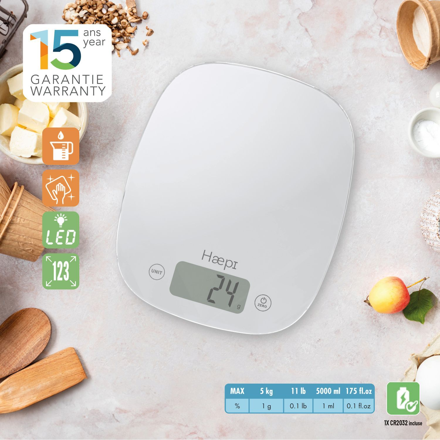 Balance de cuisine blanche avec affichage numérique indiquant 24g, entourée d'ingrédients et d'ustensiles de pâtisserie.