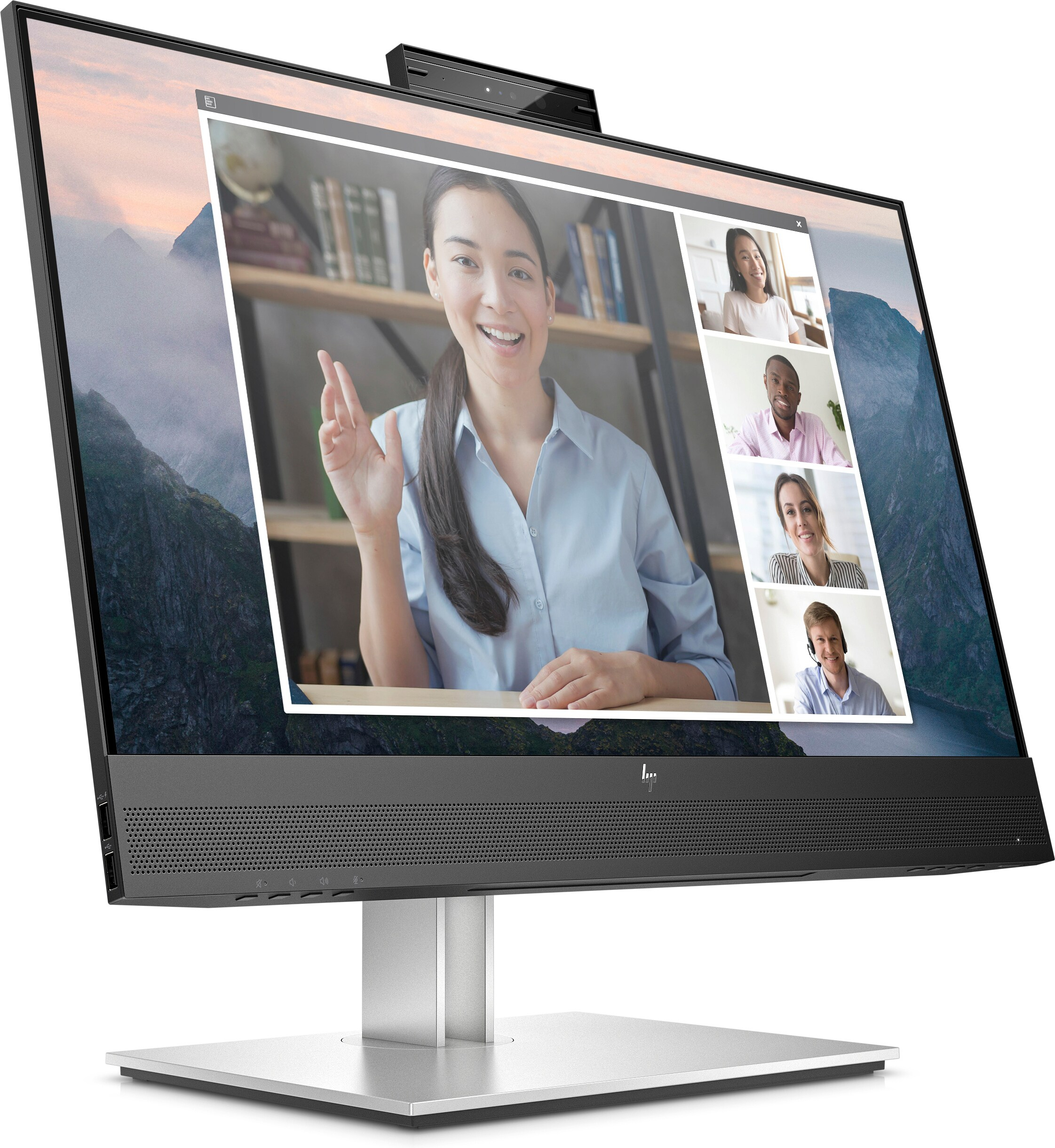 Ein Computermonitor zeigt eine Videokonferenz. Eine Frau winkt. Berglandschaft ist im Hintergrund sichtbar.