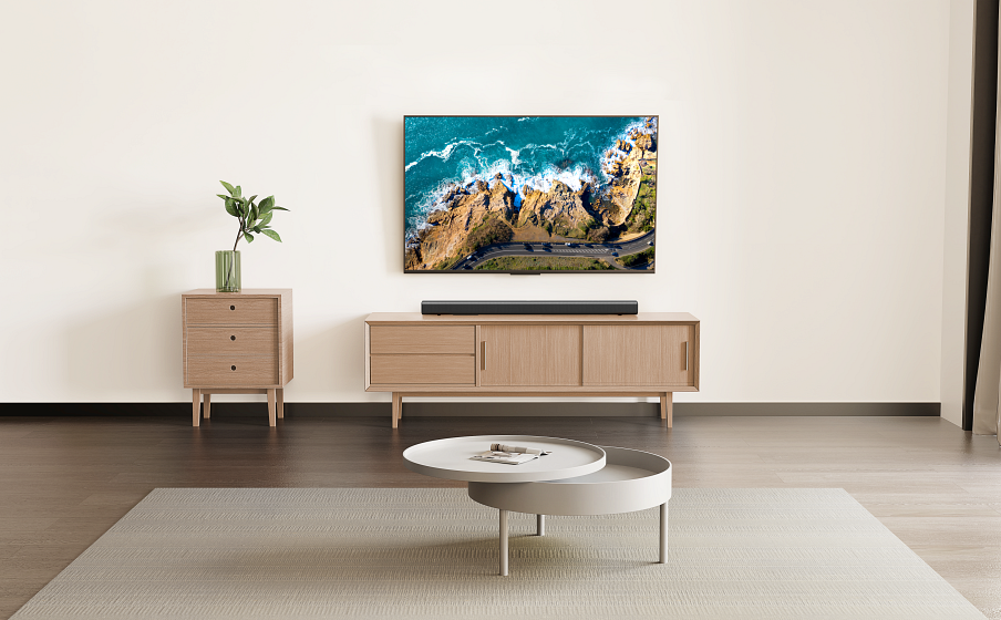 Un soggiorno con TV, soundbar, mobile e tavolino rotondo.