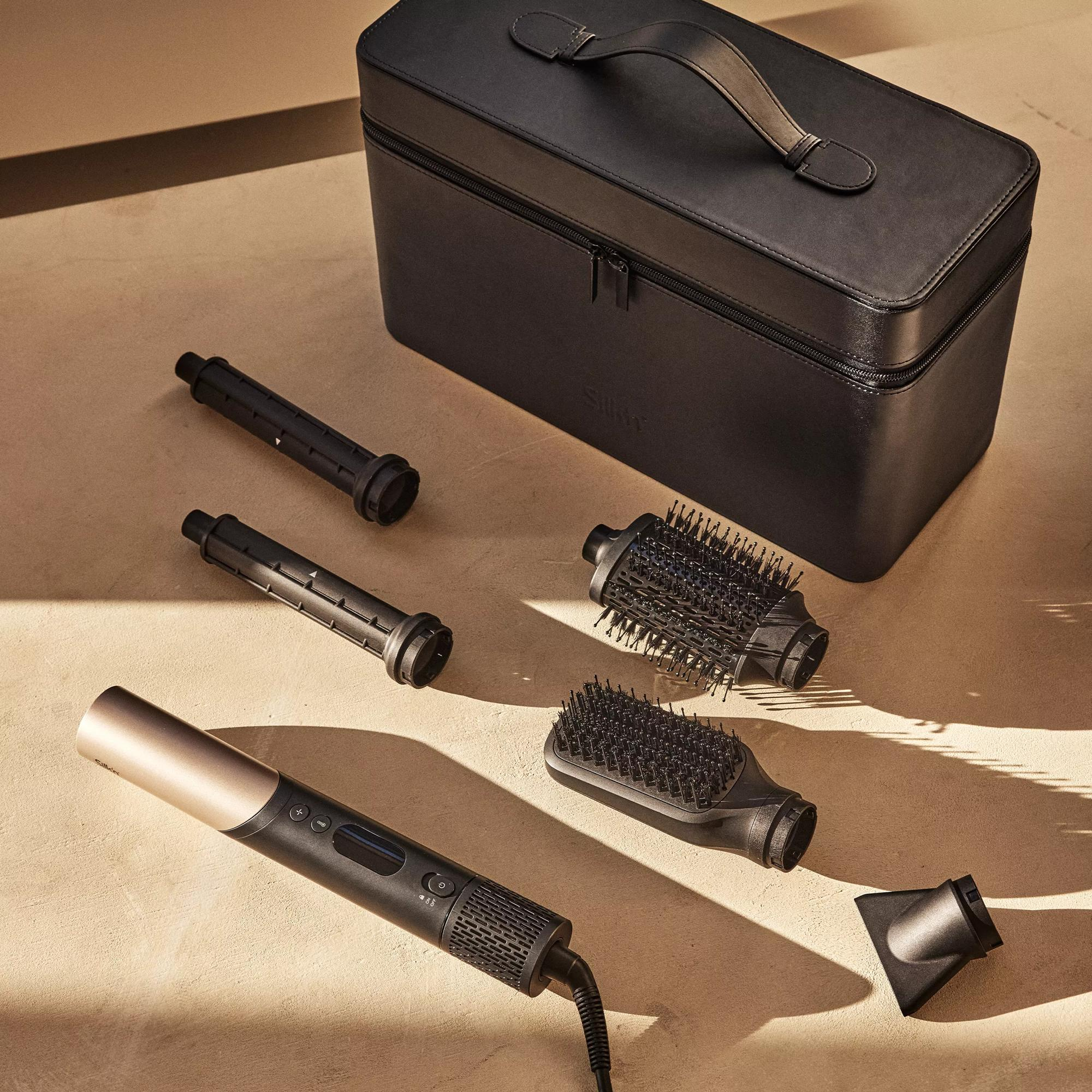 Frisur-Styling-Tools und Zubehör auf einer Oberfläche angeordnet, einschließlich eines Föhns und Bürstenköpfen.