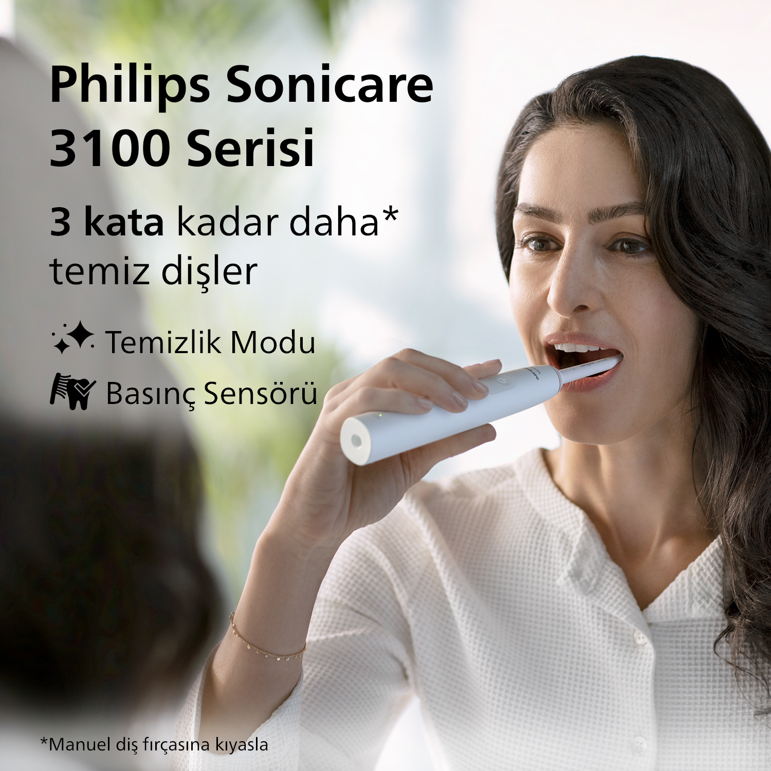 Beyaz bir Philips Sonicare elektrikli diş fırçasıyla dişlerini fırçalayan, aynada gülen bir kadın.