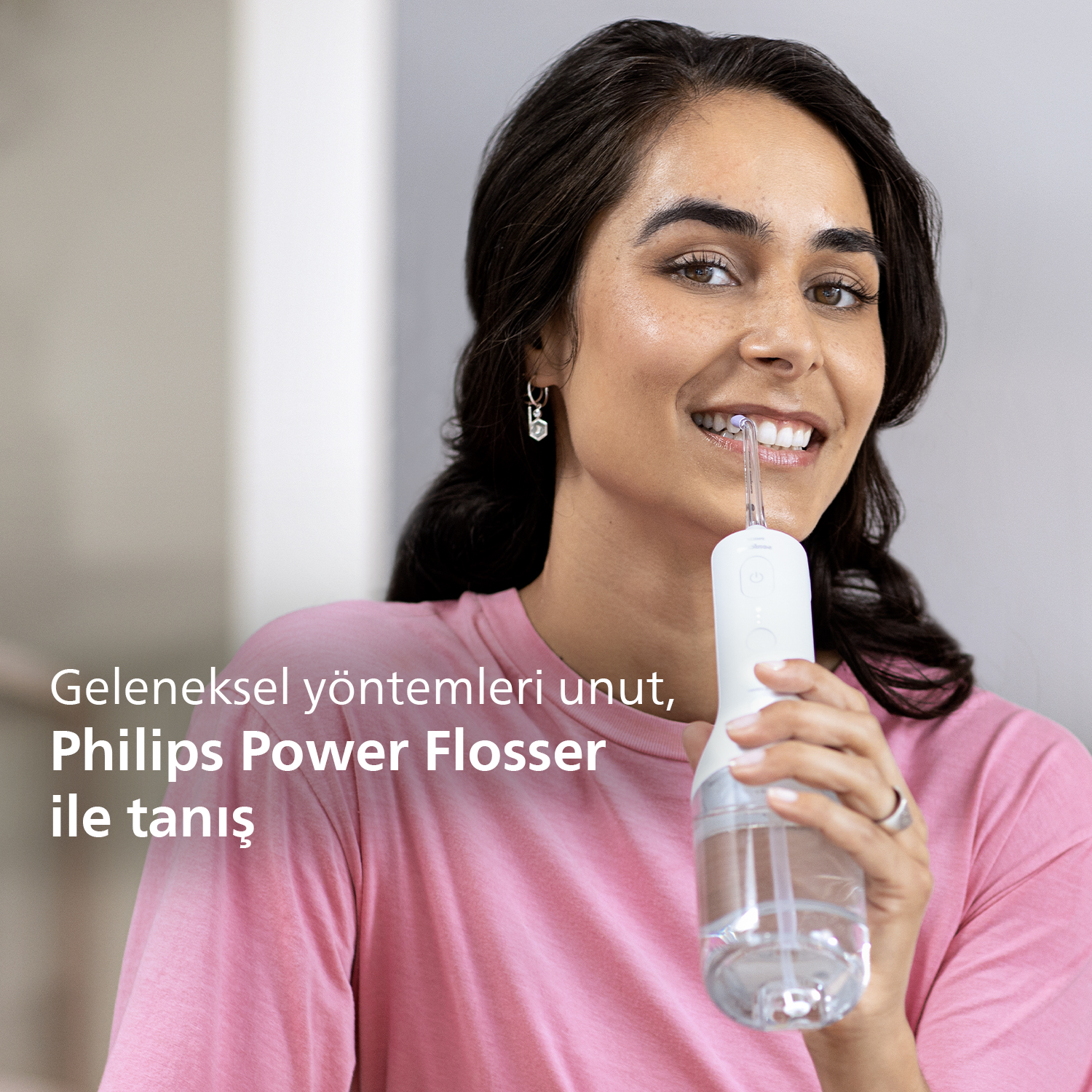 Philips Power Flosser kullanan, gülen, ürünü tanıtan metinli bir kadın.