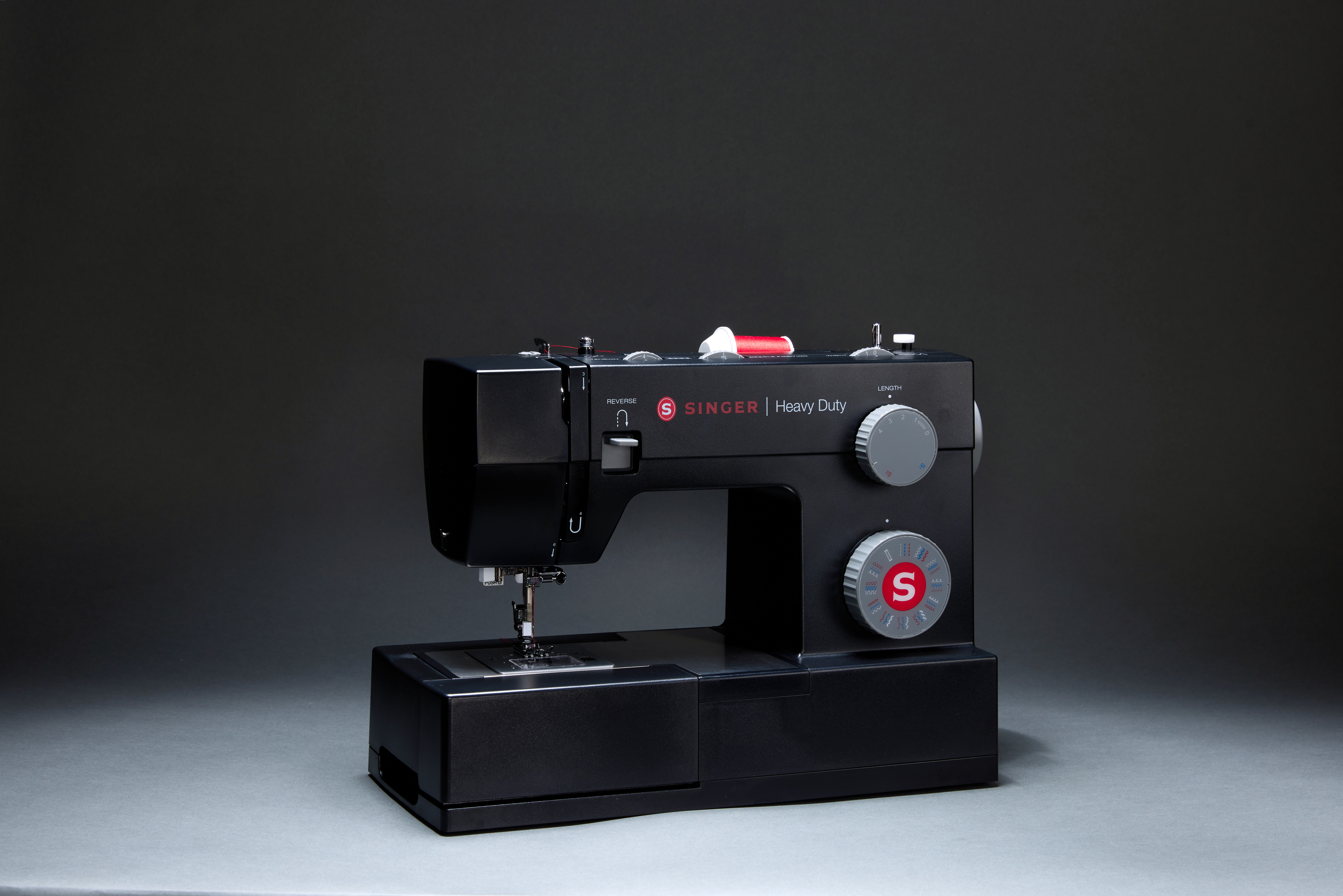 Schwarze Singer Heavy Duty Nähmaschine auf grauer Oberfläche, mit neutralgrauem Hintergrund.