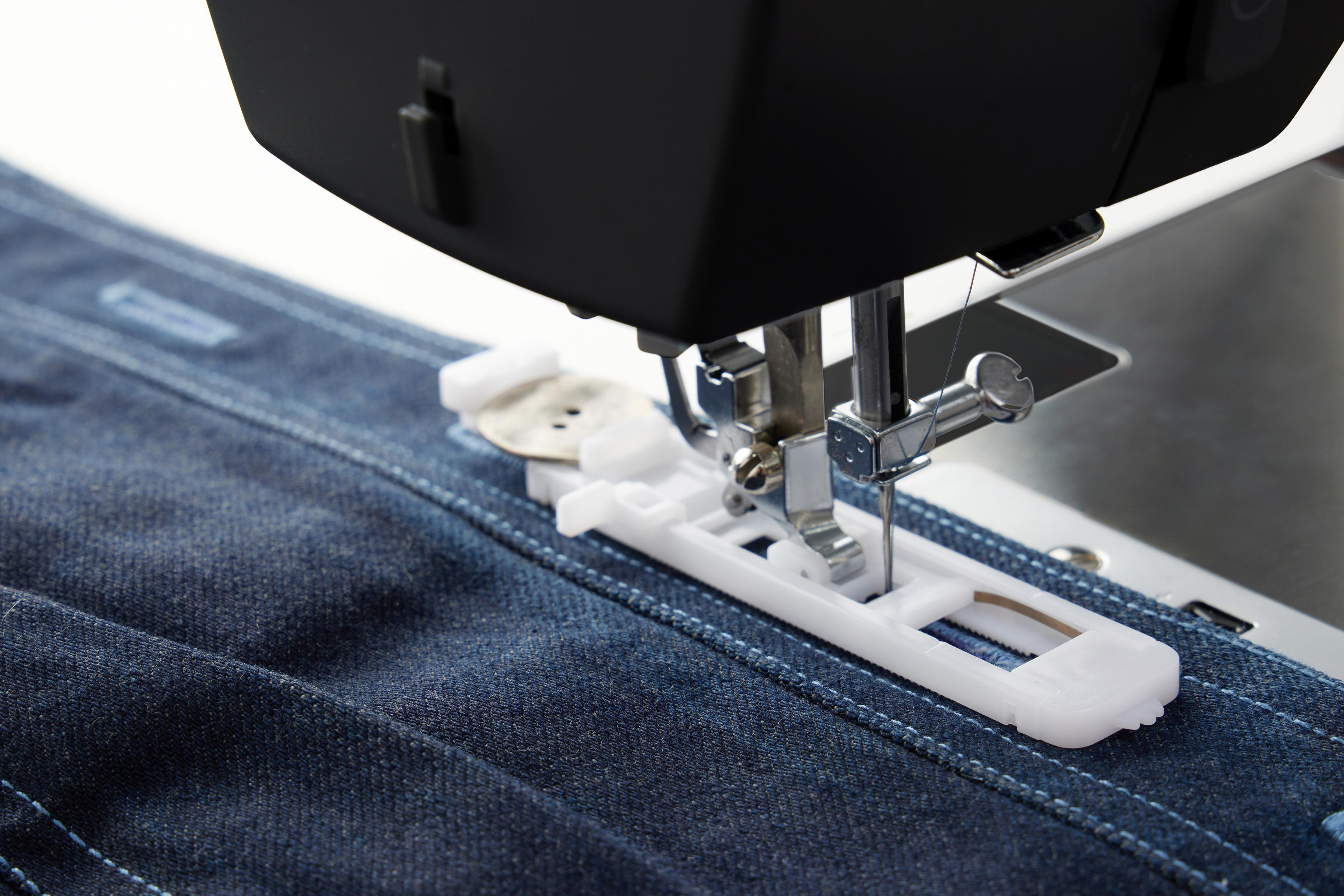 Nähmaschine mit Denim und Knopfloch-Aufsatz. Die Maschine ist schwarz und silber.