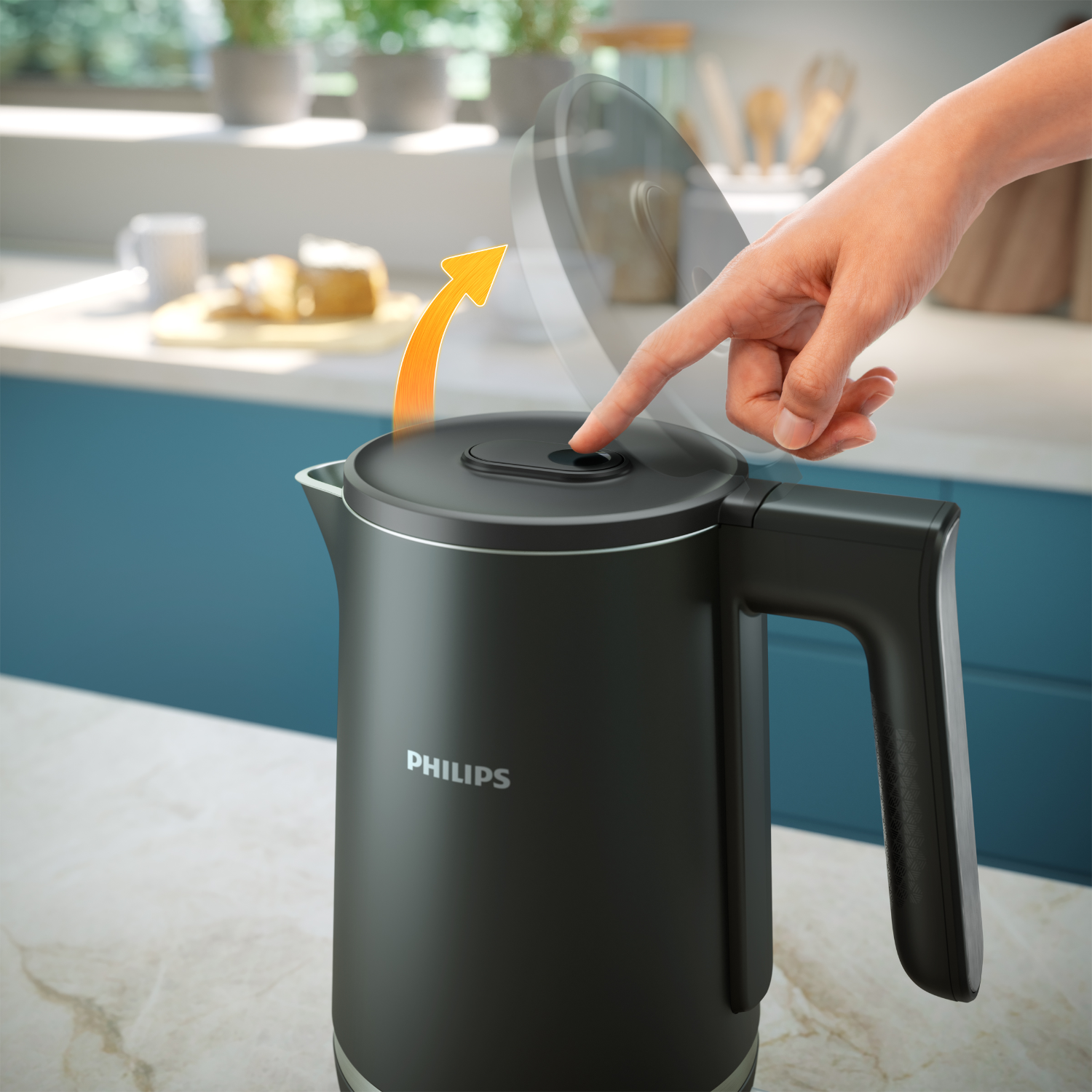 A person's finger presses a button on a black kettle, with an orange arrow indicating the action.