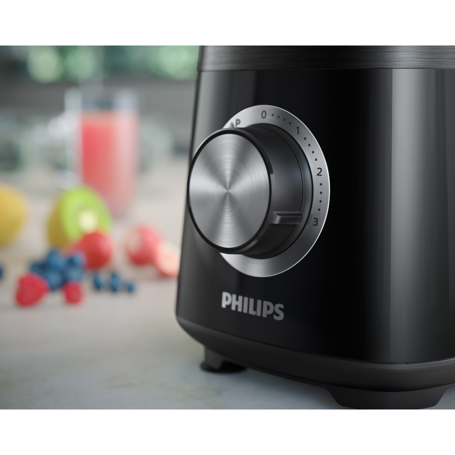 Black Philips blender with a silver dial. It is on a white surface next to fruit. The dial is at 3.