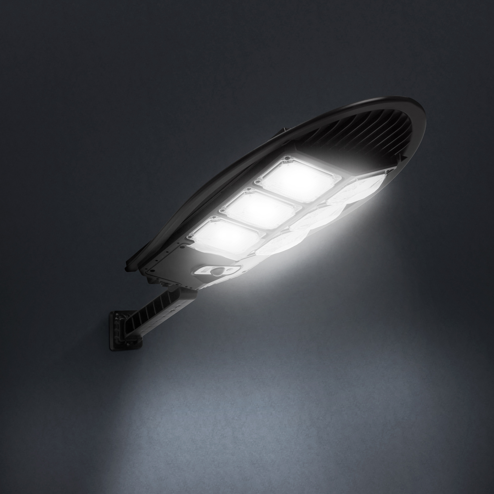 Fekete LED-es utcai lámpa. Erős fényt bocsát ki. Sötétszürke falra szerelve.