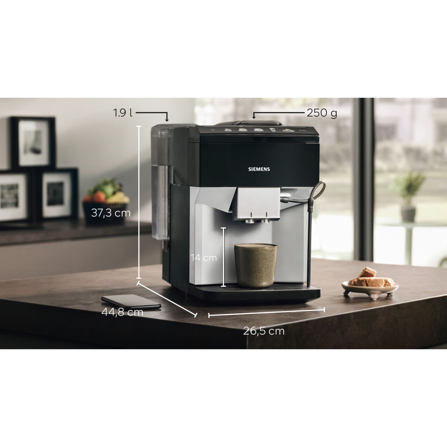 Een zwarte Siemens koffiemachine met afmetingen op een bruin aanrecht, een kopje en een klein bordje met koekjes.