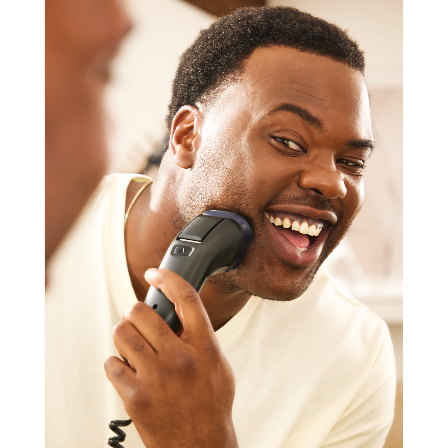 Man shaving in the mirror with a shaver.