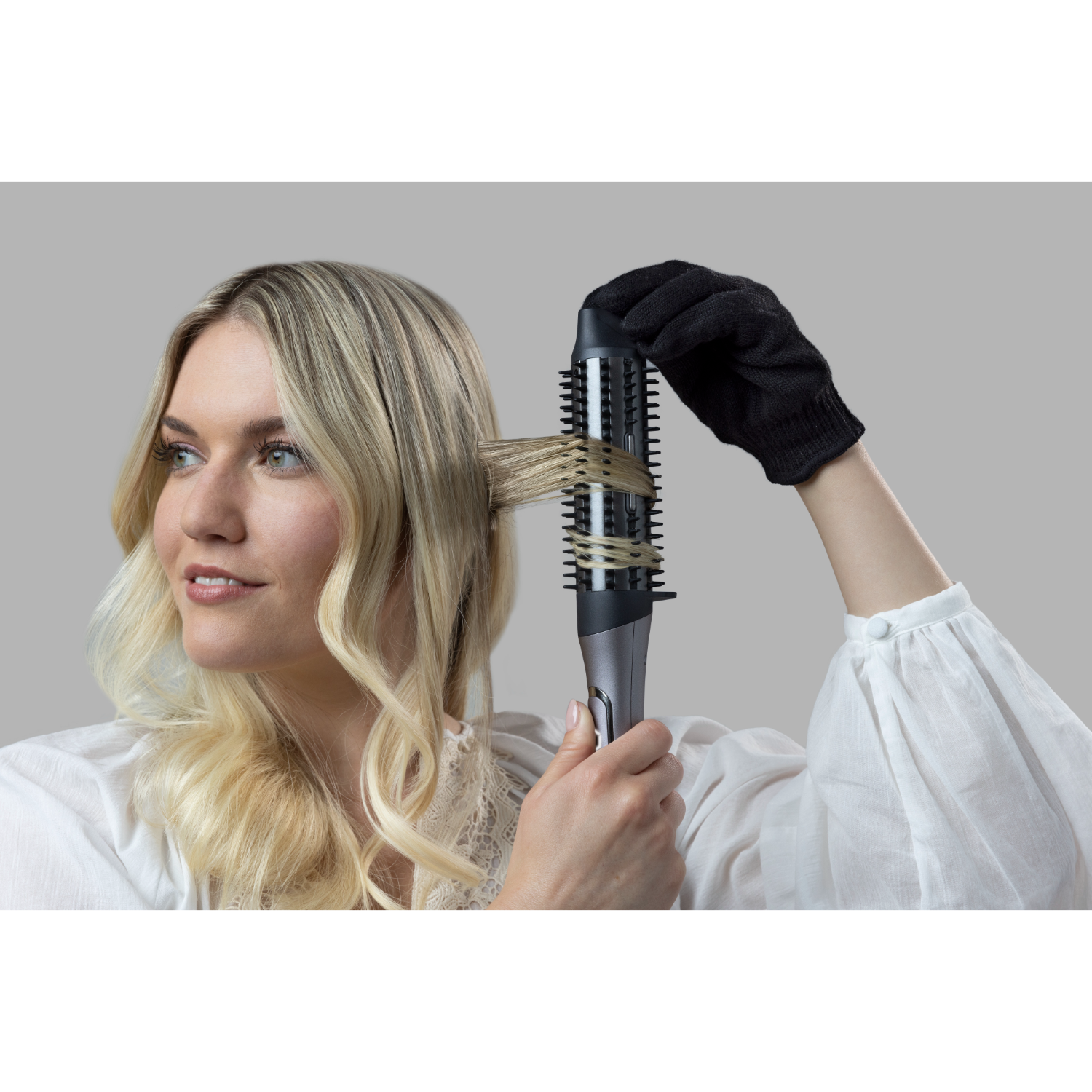 Een vrouw die haar haar stylet met een krulborstel, met een zwarte hittebestendige handschoen.