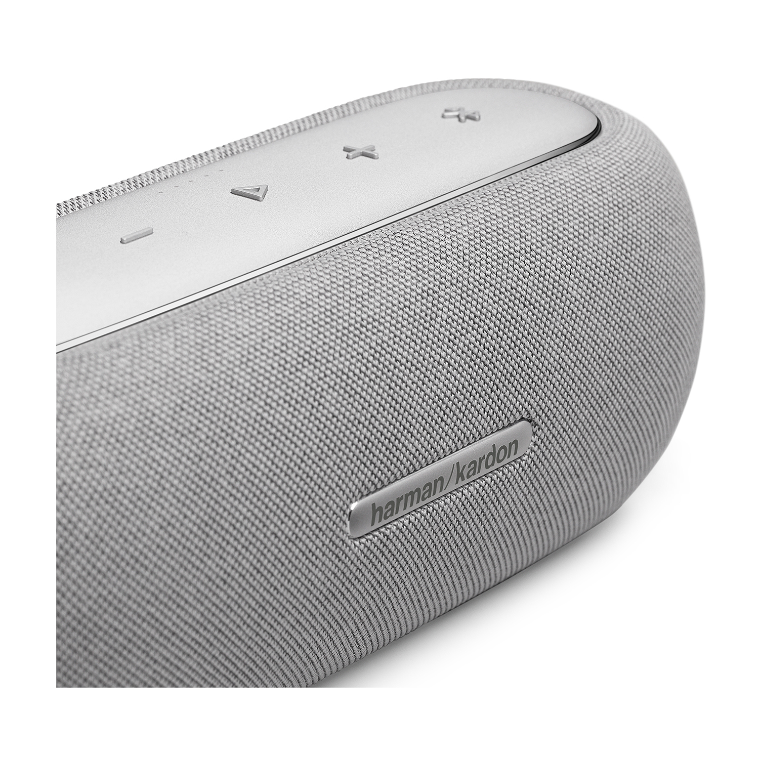 Primo piano di un altoparlante. Rivestimento in tessuto grigio con il logo Harman/Kardon. Sfondo bianco.