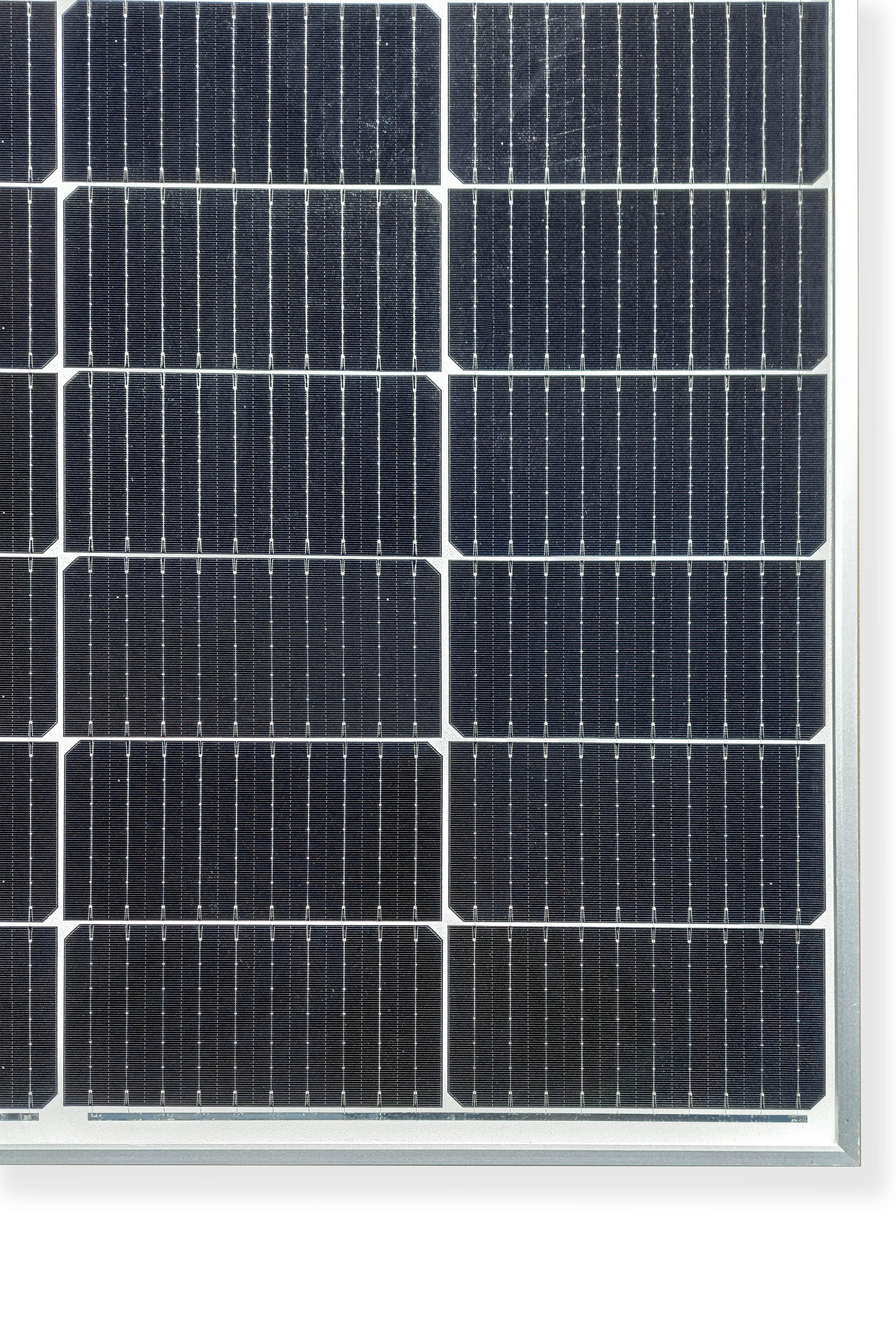 Nahaufnahme eines Solarmoduls. Dunkle Quadrate mit weißen Linien. Silberner Rahmen, weißer Hintergrund.