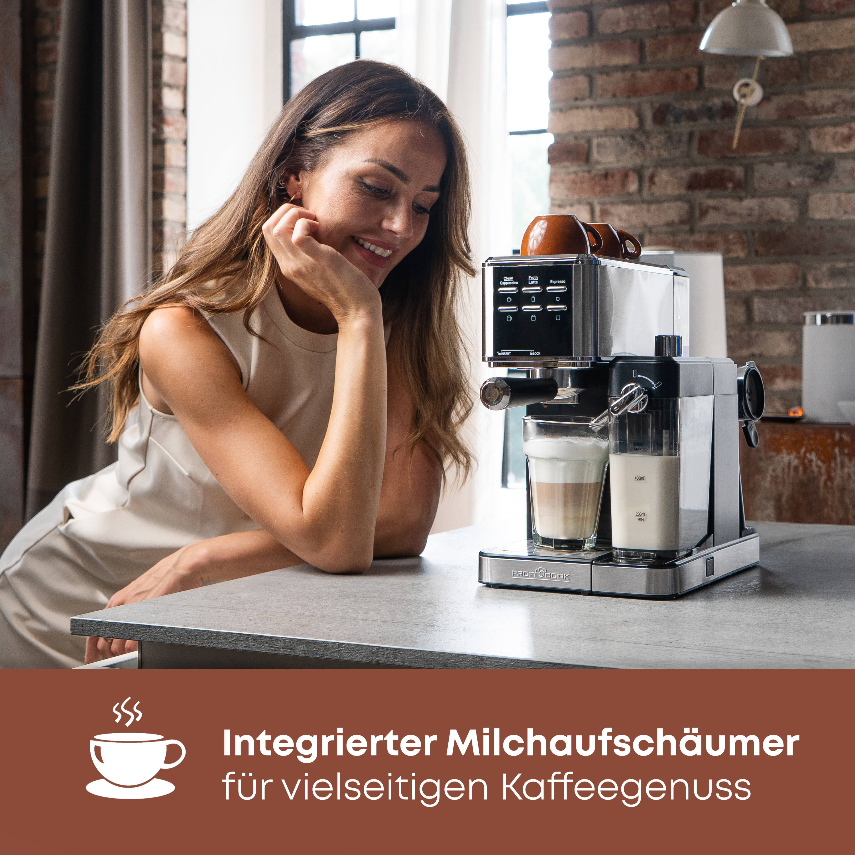 Frau lächelt eine Espressomaschine an. Zu den Merkmalen gehört ein integrierter Milchaufschäumer.