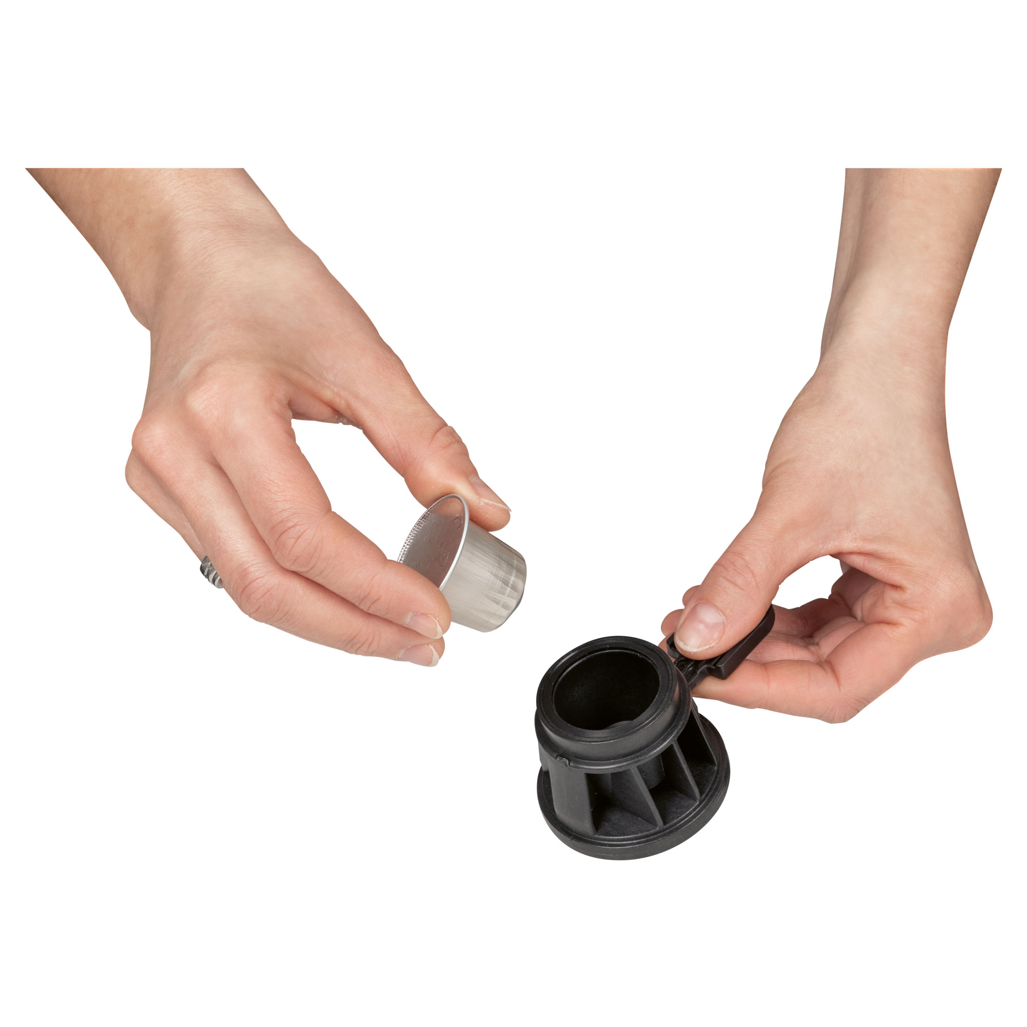Hände bereiten eine Kaffeekapsel vor. Eine Hand hält die Kapsel, die andere ein Kaffeemaschinenteil.
