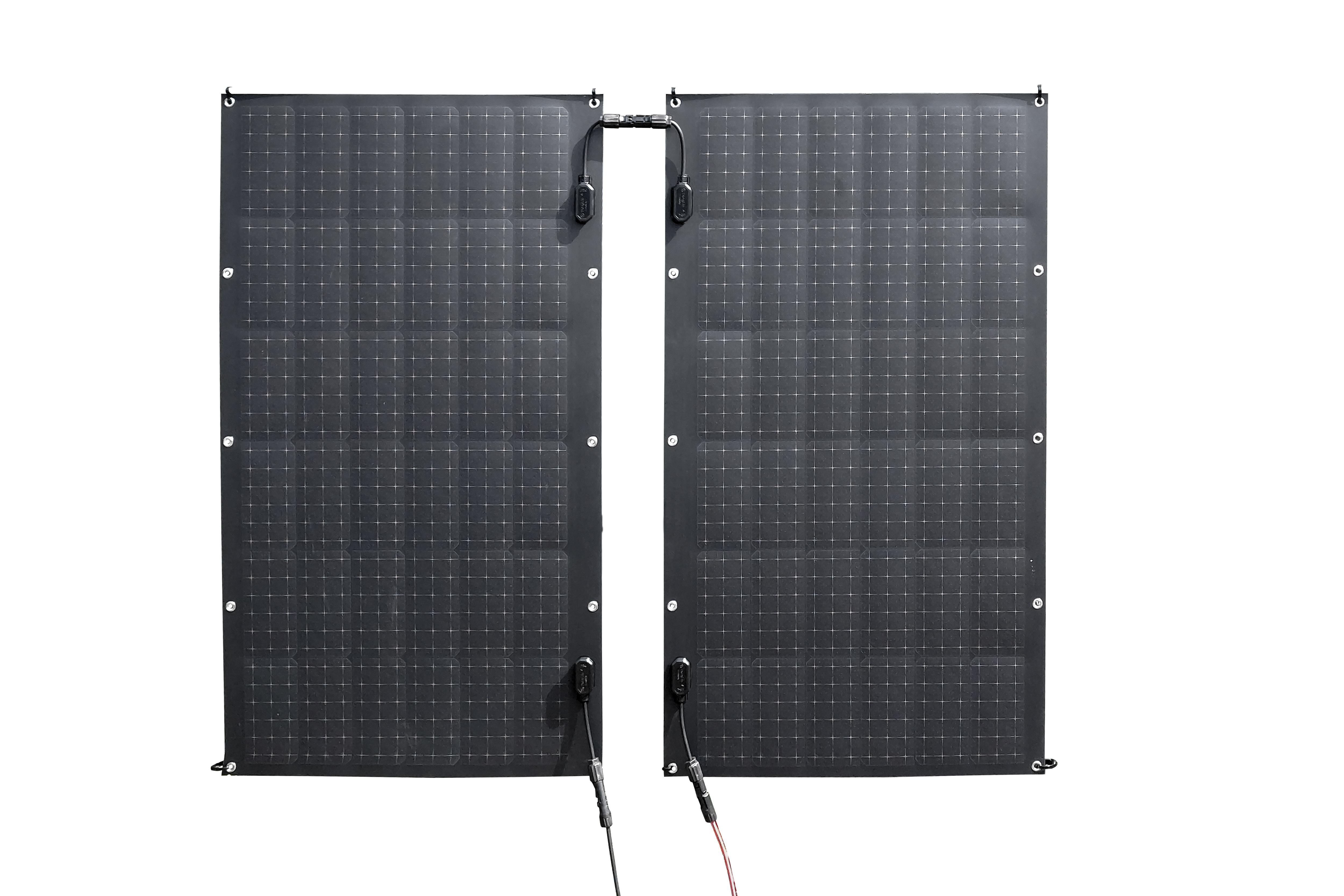 Zwei schwarze Solarmodule mit sichtbaren Quadraten. Sie sind durch ein Kabel verbunden.
