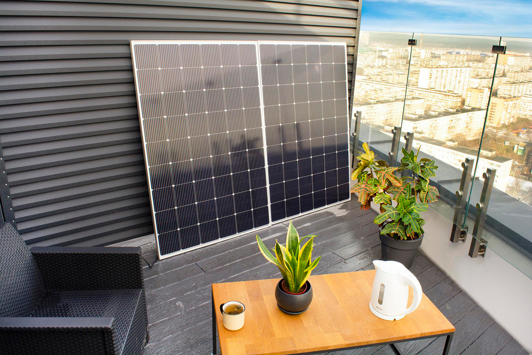 Balkon mit Solarmodulen, Pflanzen, einem Tisch und Blick auf die Skyline der Stadt.
