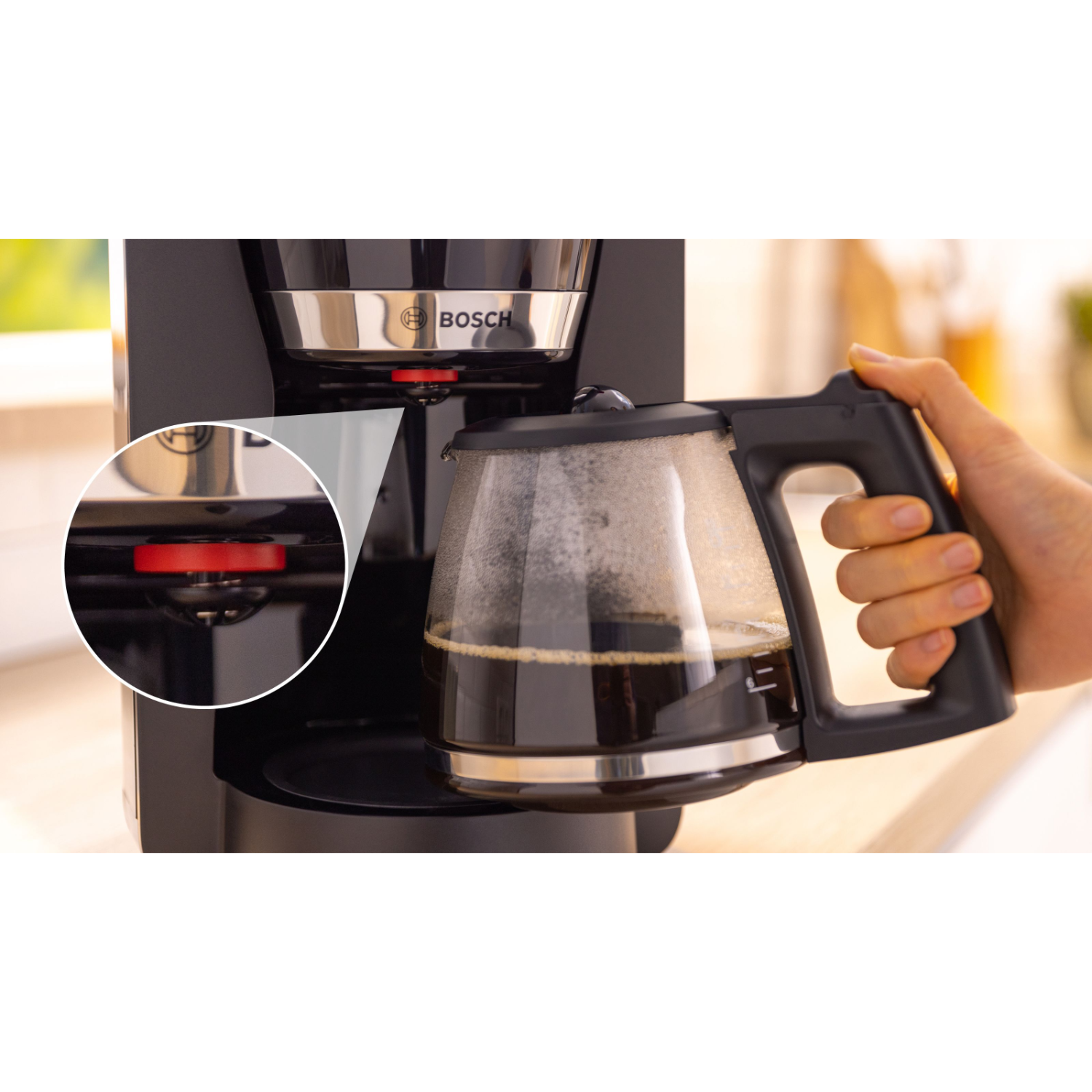 Een hand houdt een koffiepot vast en vult hem met koffie uit een koffiezetapparaat. Een rode knop staat centraal.