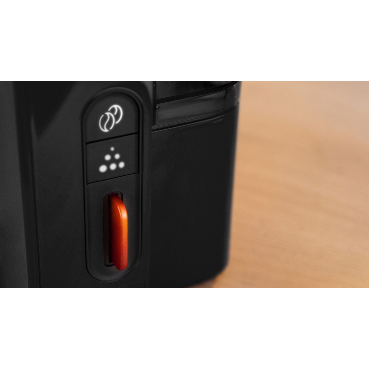 Close-up van een zwarte machine met een oranje hendel en drie witte lichtgevende stippen.