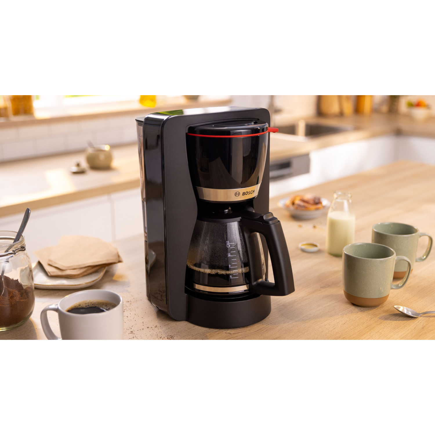 Zwarte koffiezetapparaat op houten tafel, koffiekop, gemalen koffie, filters, mokken, melkfles. Keukenachtergrond.