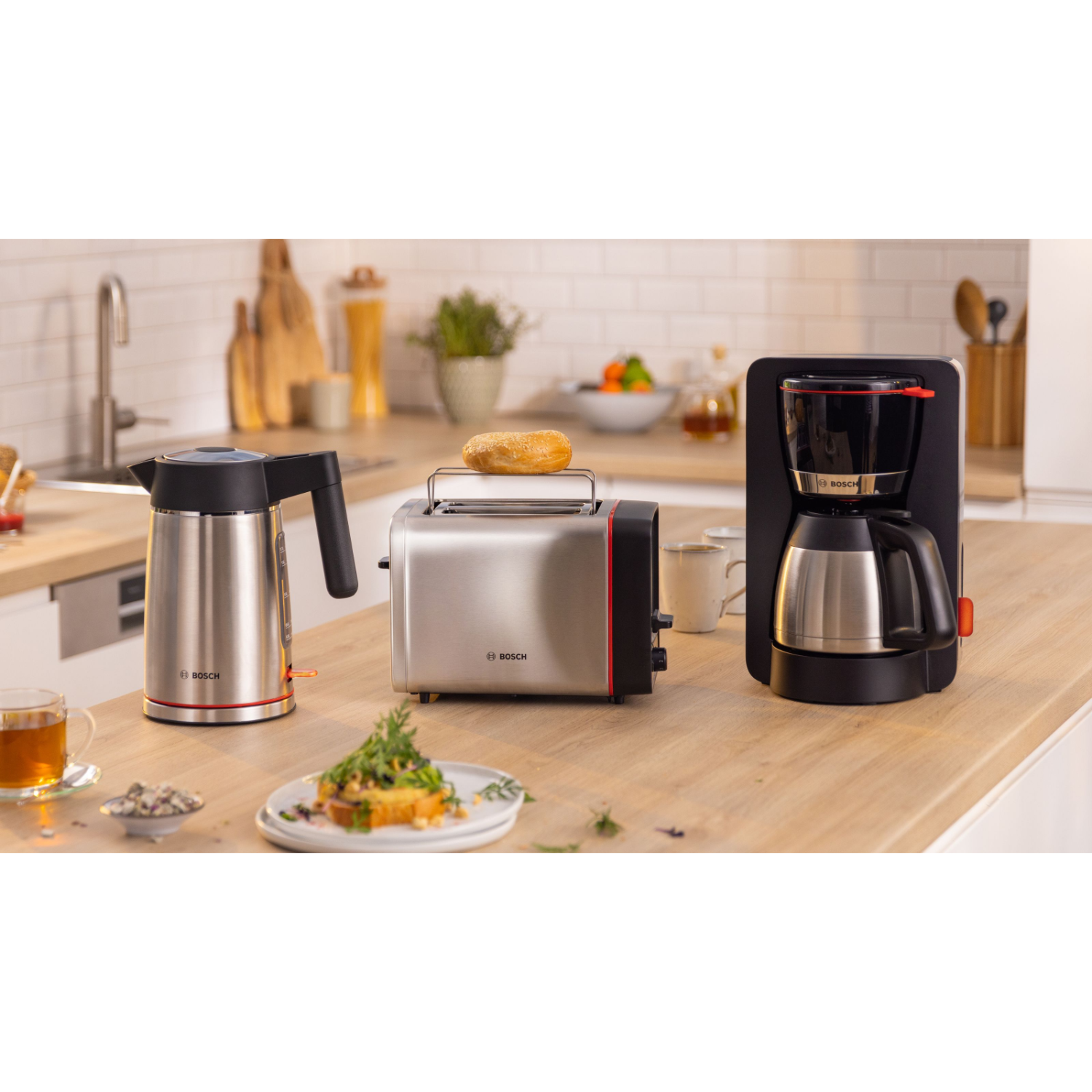 Keukenblad met Bosch-apparaten: waterkoker, broodrooster met bagel, koffiezetapparaat en etenswaren.